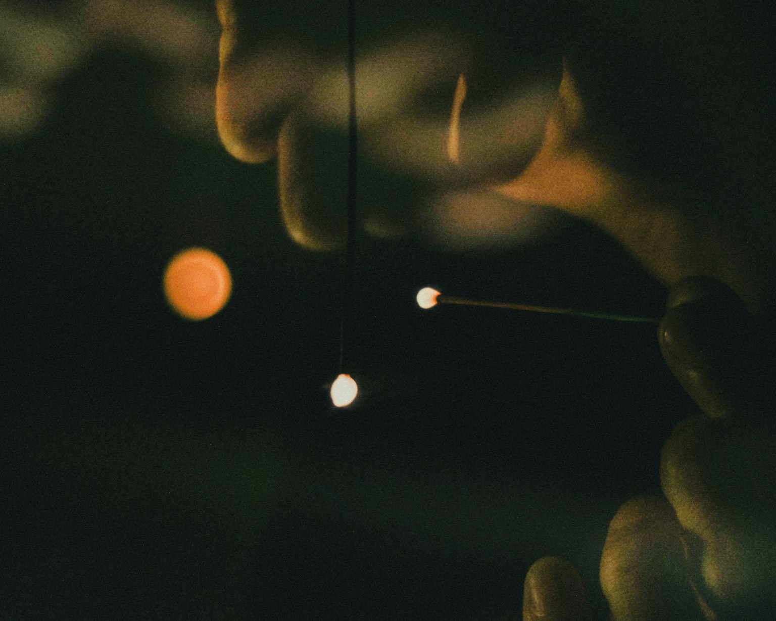 Gros plan de mains tenant de petites sphères lumineuses sur fond sombre