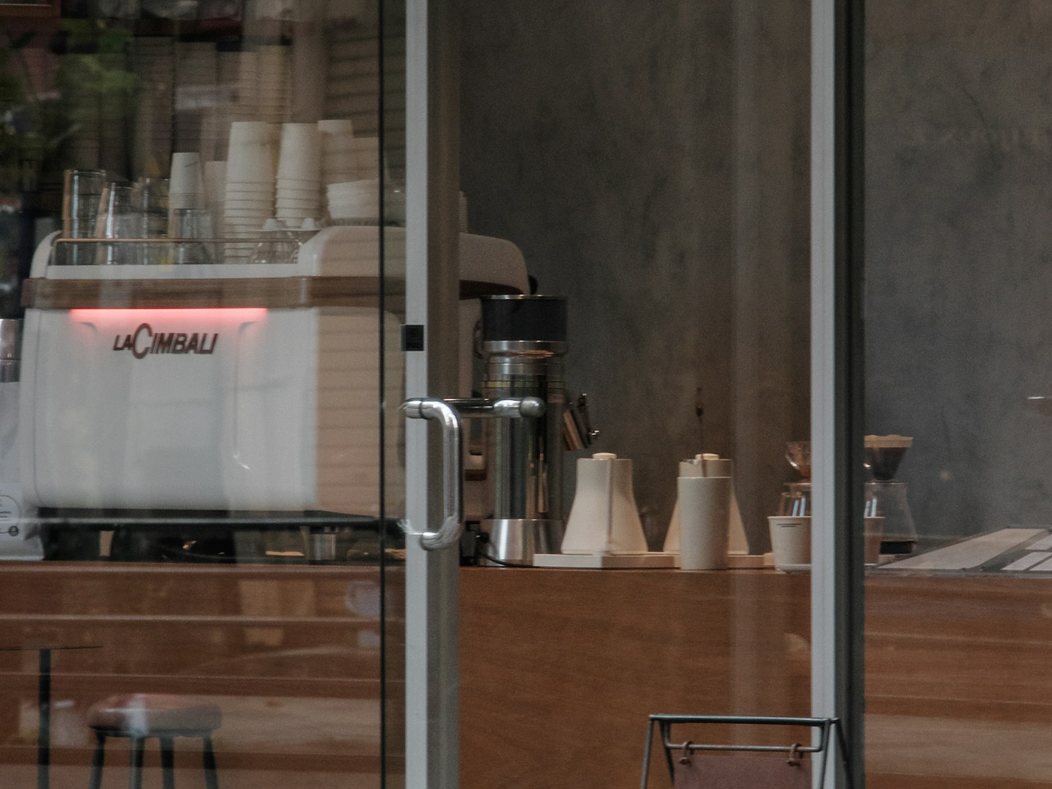 Nội thất của quán cà phê nhìn thấy qua cửa kính với máy pha cà phê espresso hiện đại và thiết bị pha cà phê