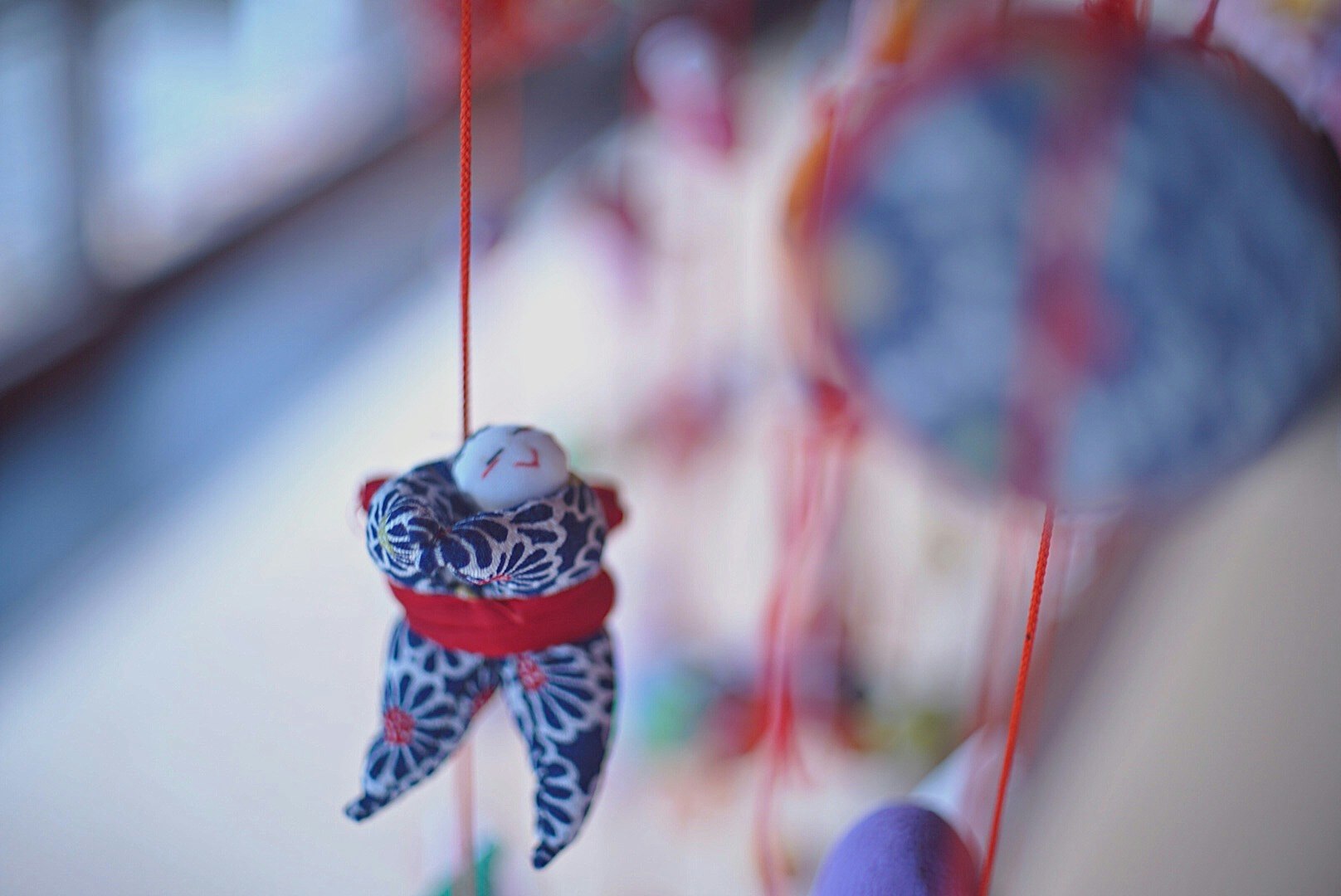 ornamen kecil yang digantung dengan tali merah dan dinding dekoratif yang buram