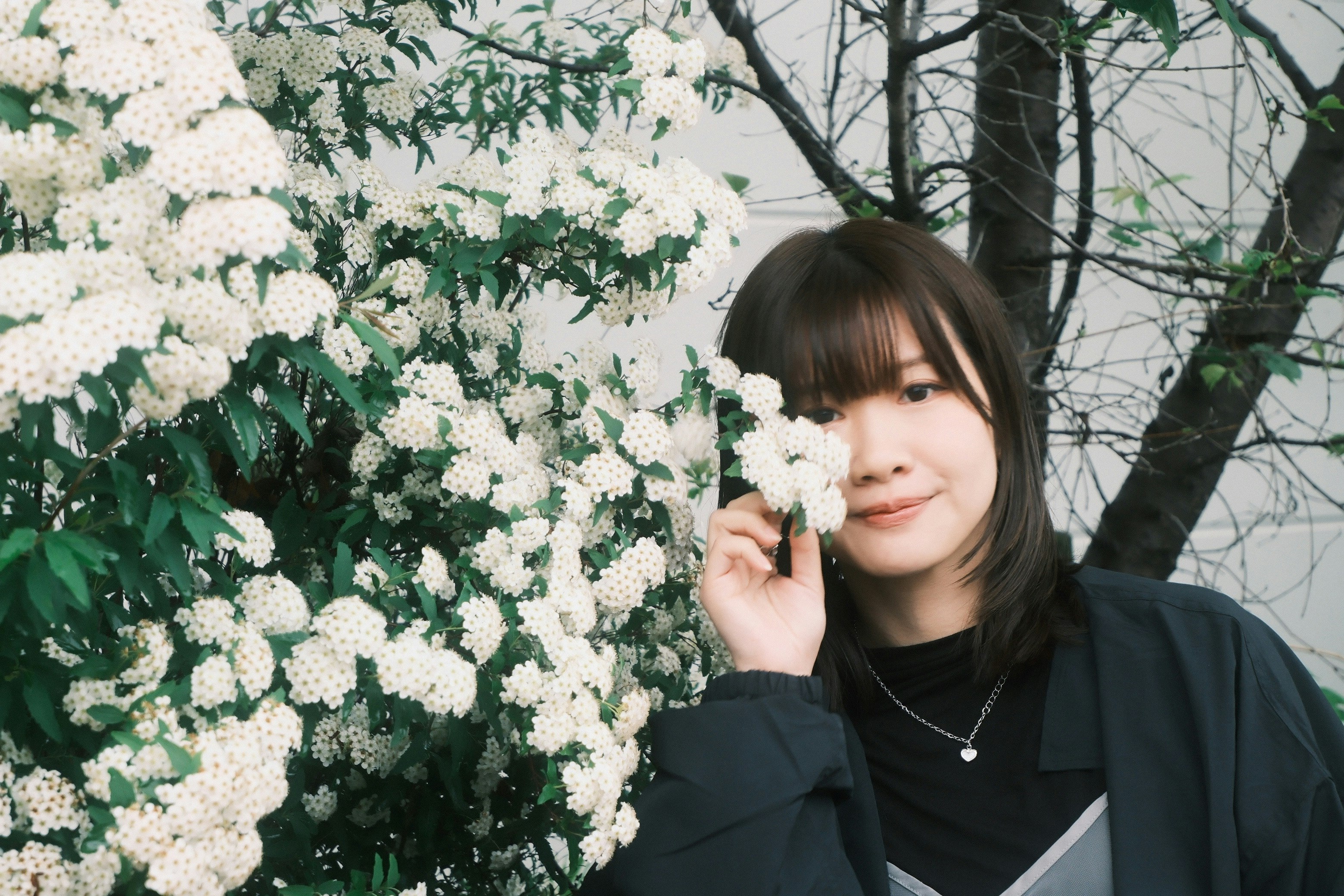 白い花の前でスマホを持つ女性