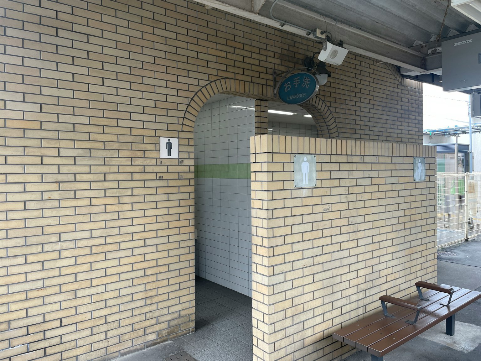 Pintu toilet dengan dinding bata di stasiun kereta