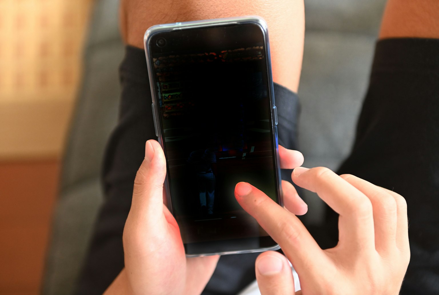 A person holding a smartphone while interacting with the touchscreen