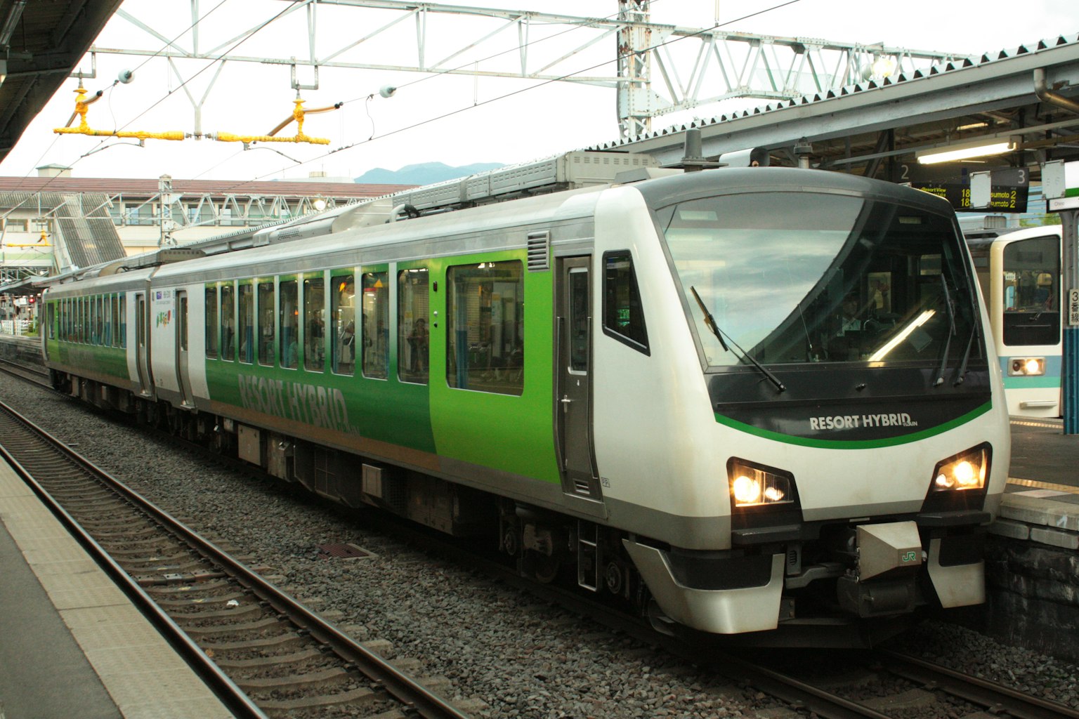 Sebuah kereta hijau dan putih diparkir di stasiun
