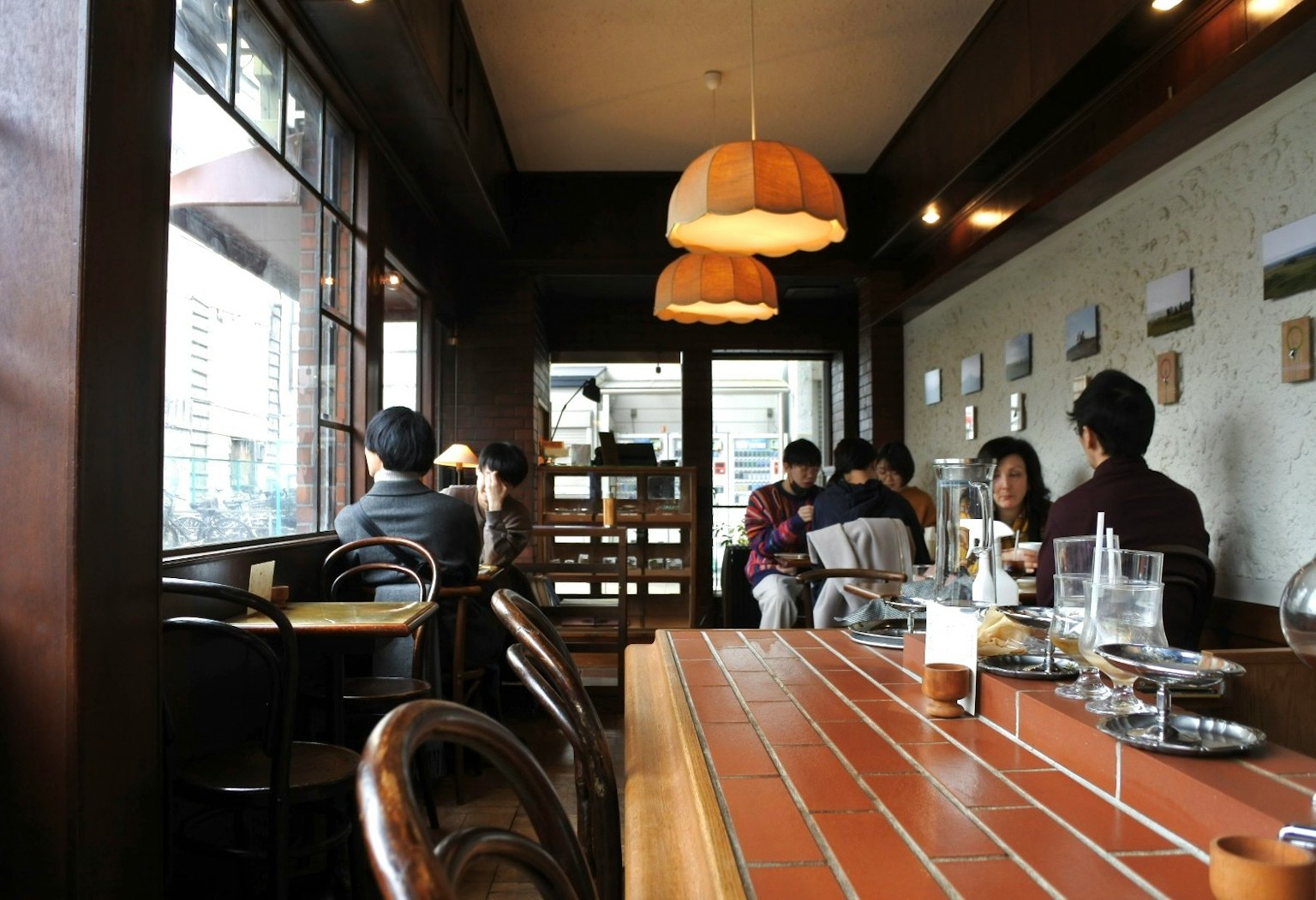 Vista interna di un caffè con tavoli e sedie in legno e illuminazione soffusa