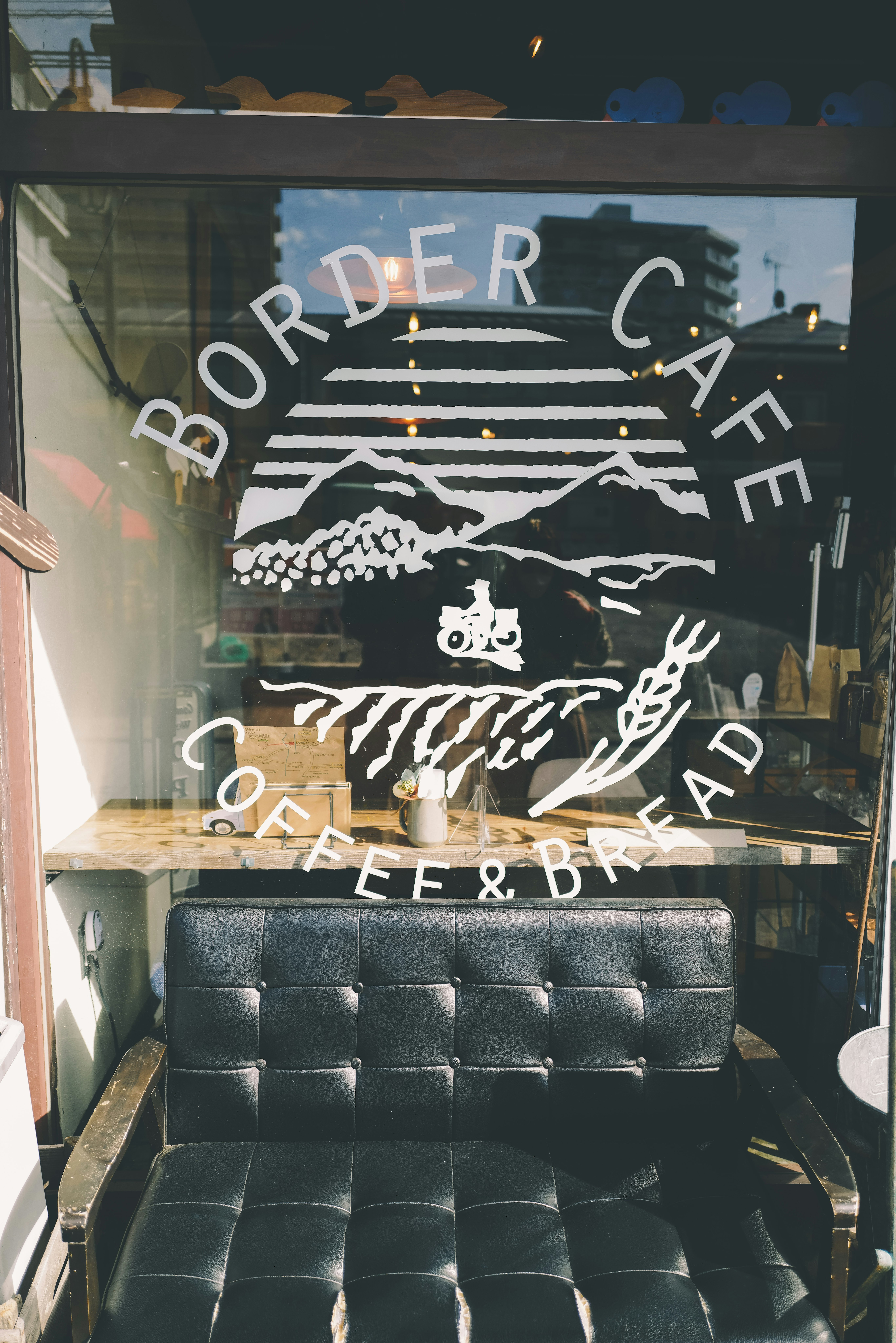 窓ガラスに描かれたイラストと「ORDER CAFE」看板のあるカフェ店内