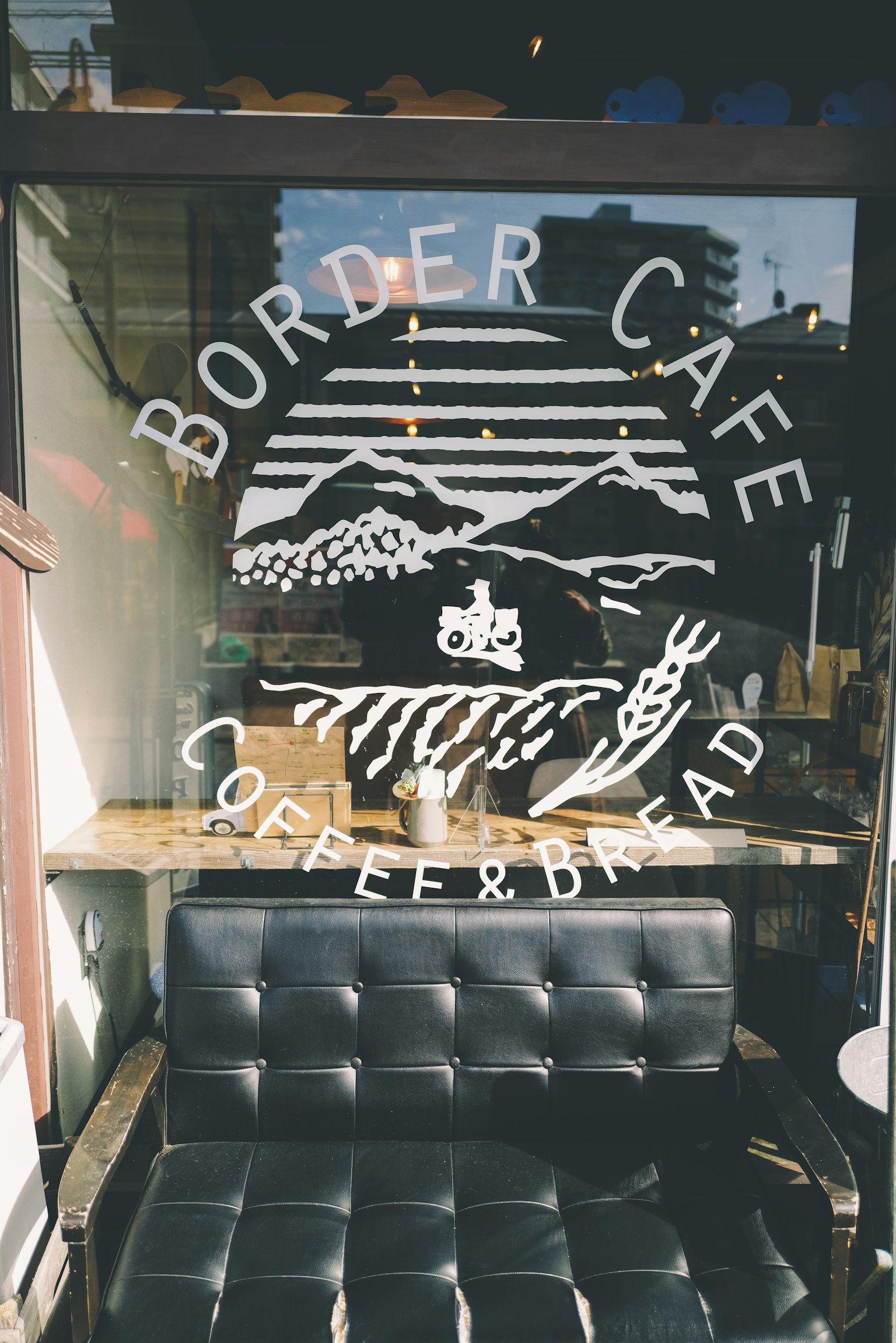 โลโก้ของ Border Café บนหน้าต่างพร้อมโซฟาสีดำข้างหน้า