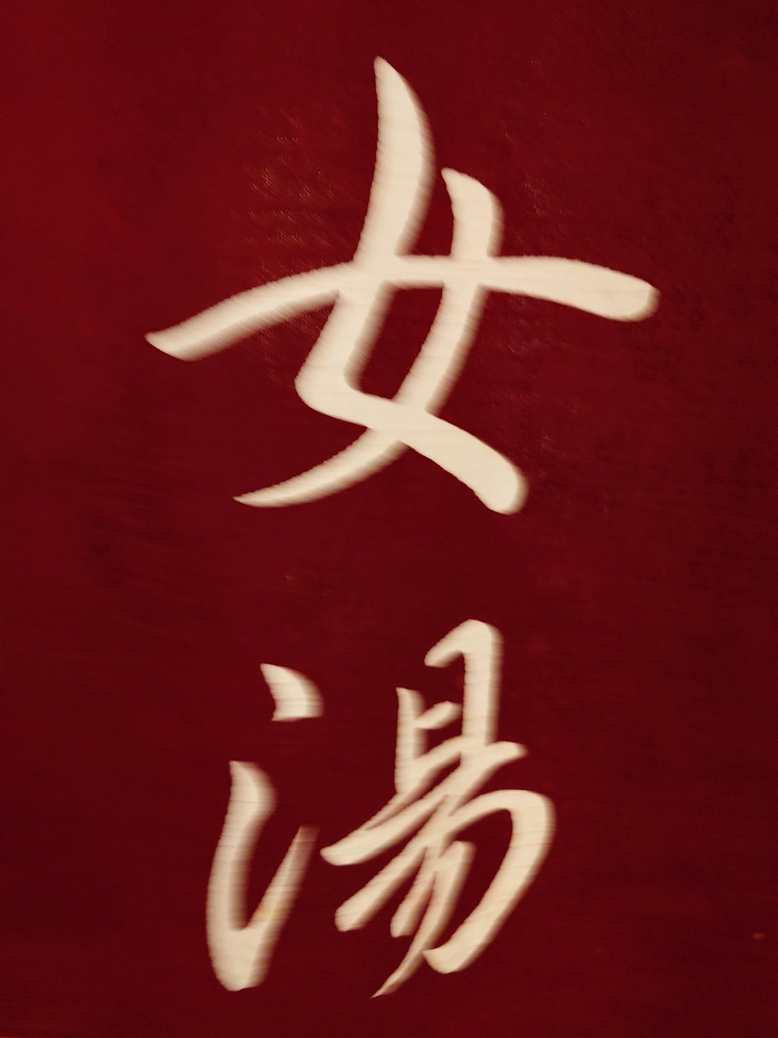 Fond rouge avec des caractères chinois blancs pour 'Bain des femmes'