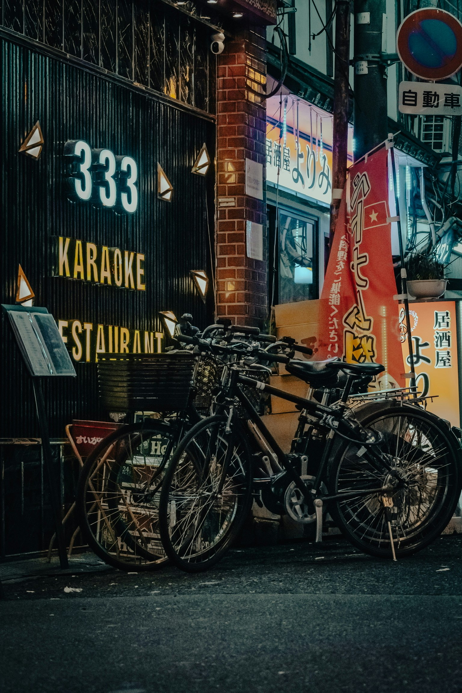 Biciclette parcheggiate in un vicolo buio accanto a un'insegna di ristorante karaoke