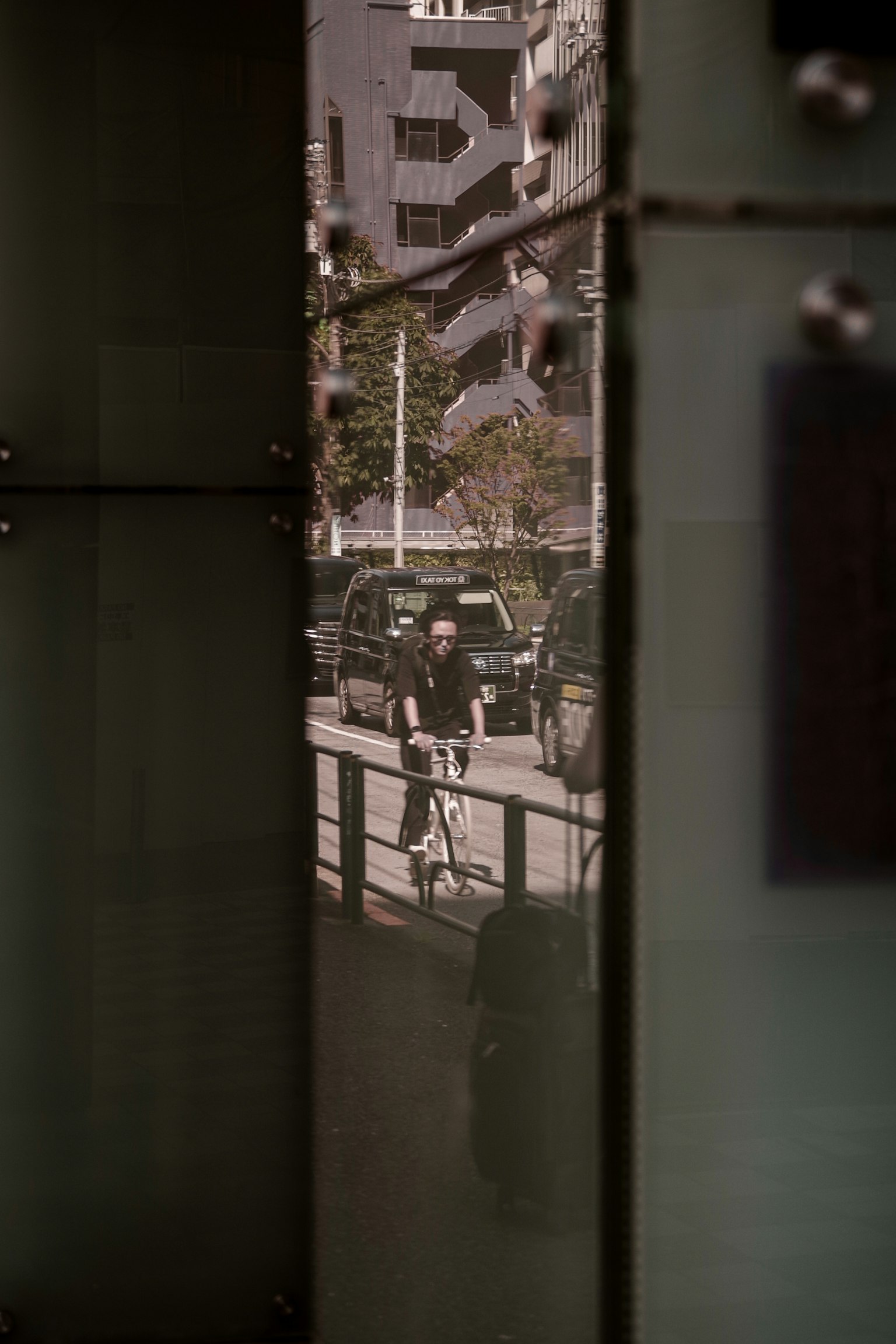 Cityscape viewed through a glass gap with a person riding a bicycle