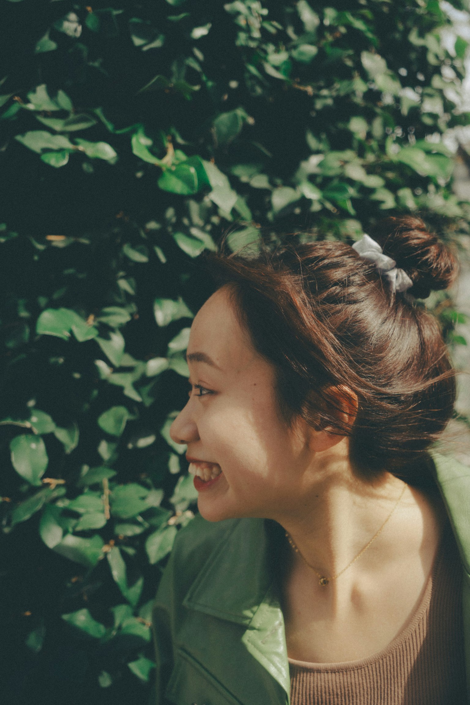 Hình ảnh nghiêng của một người phụ nữ cười trước lá xanh