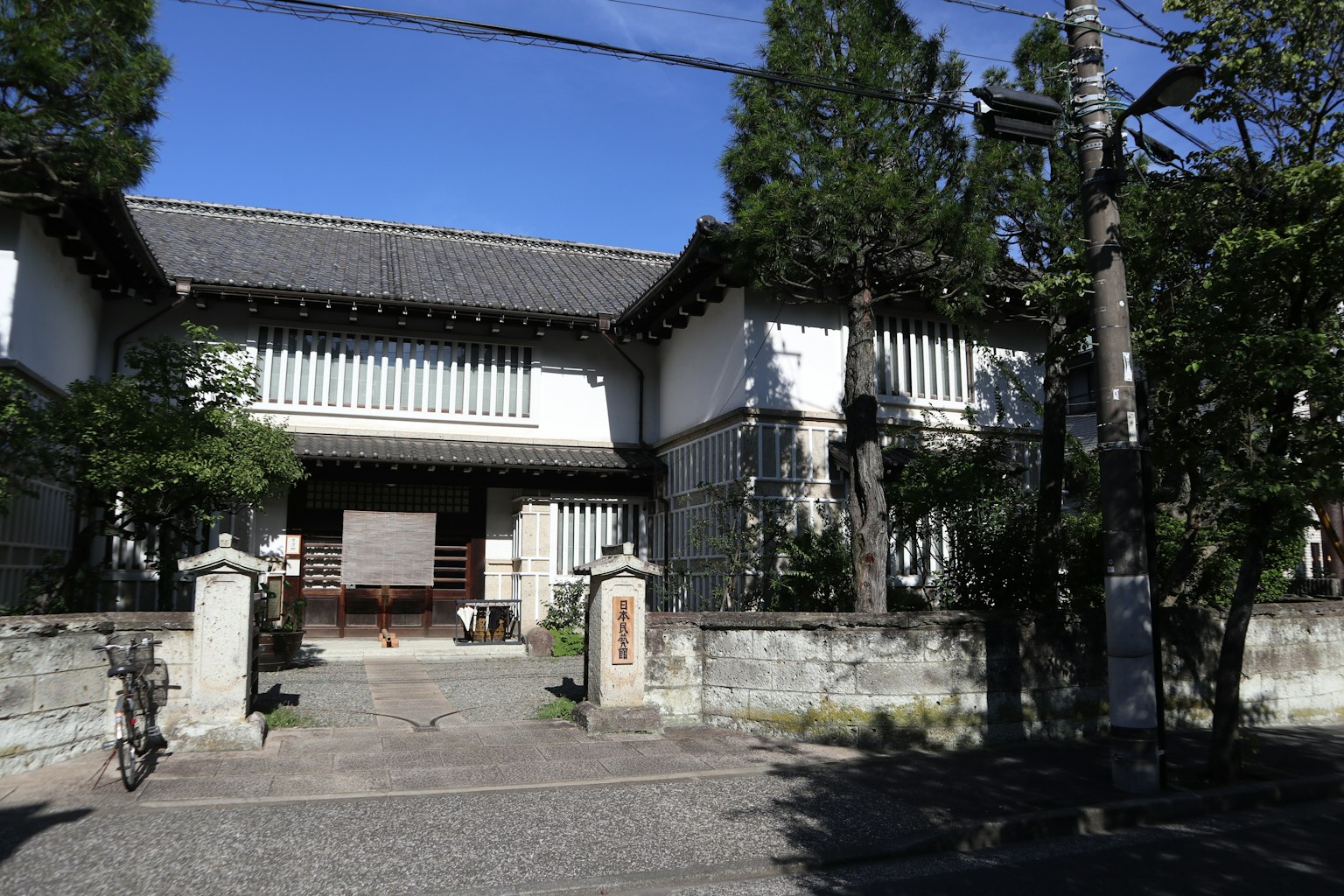 老式日本房屋的外观 特色是郁郁葱葱的花园和石头围墙