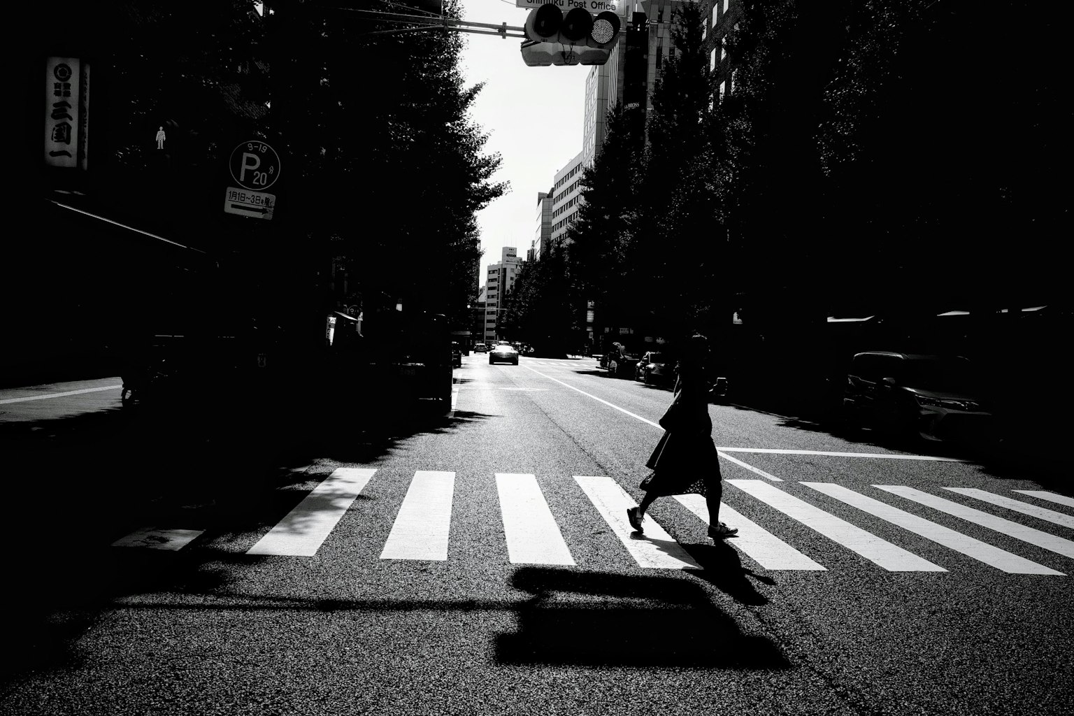 Silhouette seseorang melintasi zebra crossing hitam dan putih di jalan kota
