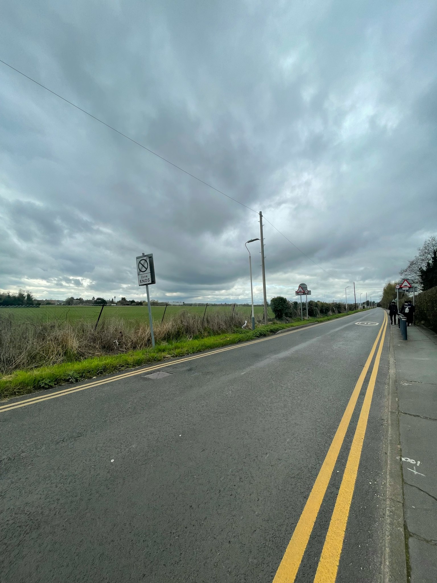 Una carretera bajo un cielo nublado con vista a campos de hierba