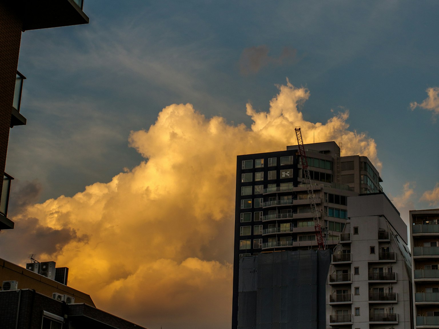 Silhouette of a skyscraper with illuminated clouds at sunset