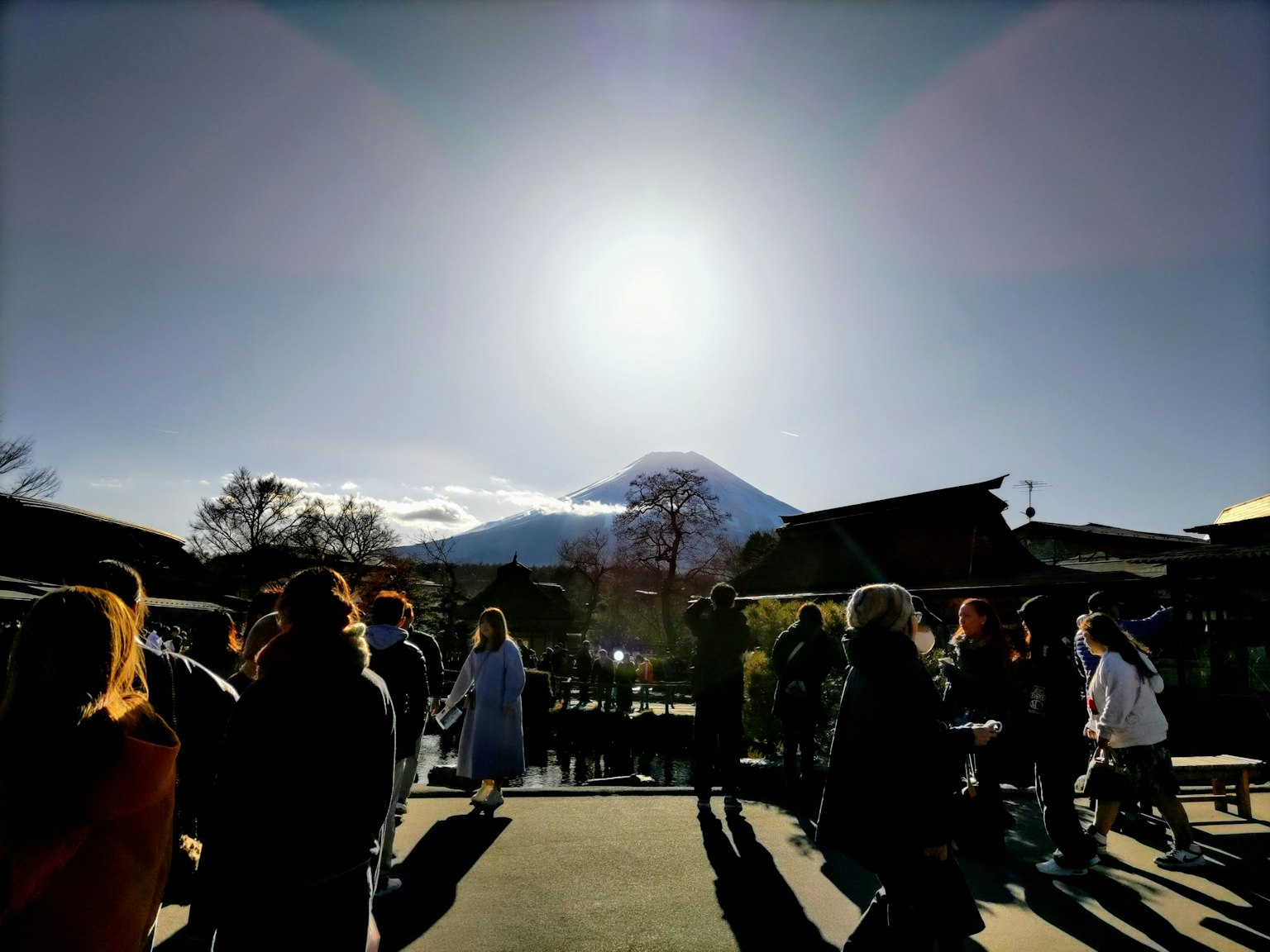 Folla di turisti con il monte Fuji sullo sfondo e sole luminoso