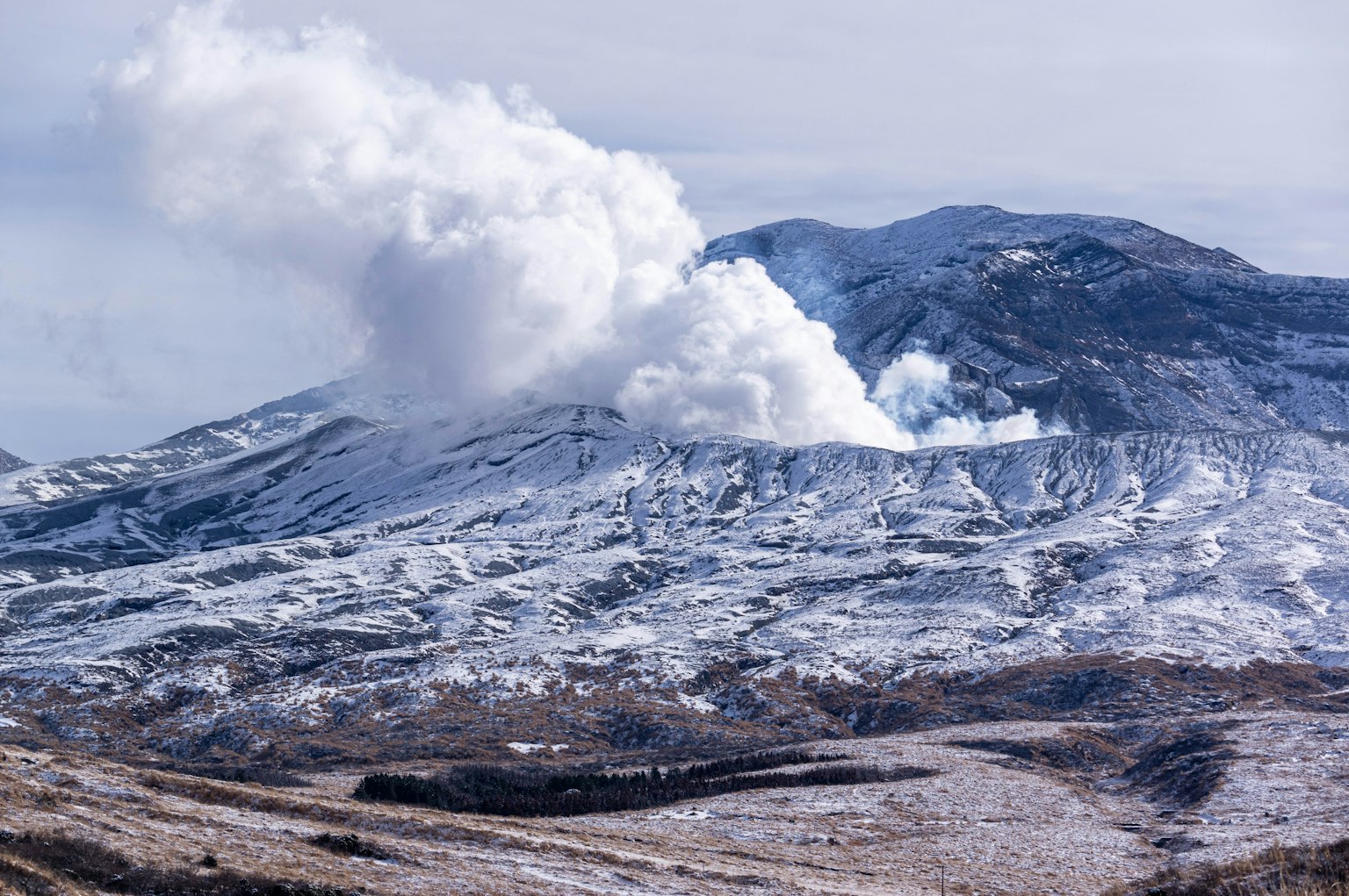 Snow-covered mountain with volcanic ash clouds