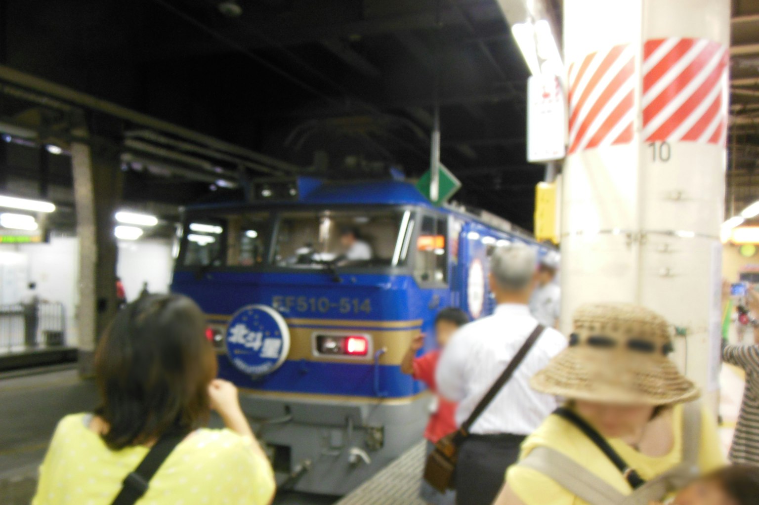 Train bleu arrivant à la gare avec des passagers autour