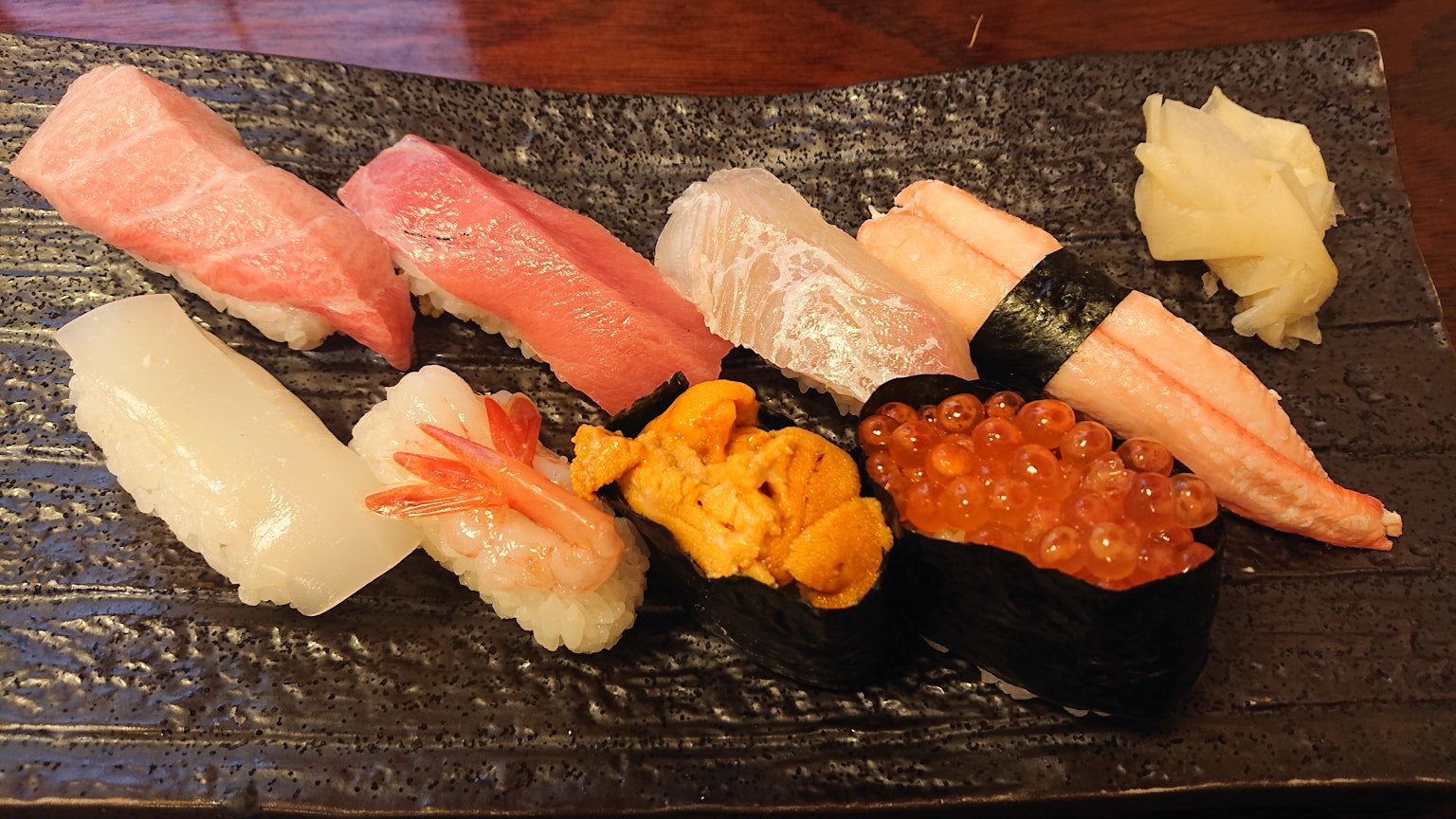 Ein buntes Sushi-Sortiment auf einem schwarzen Teller