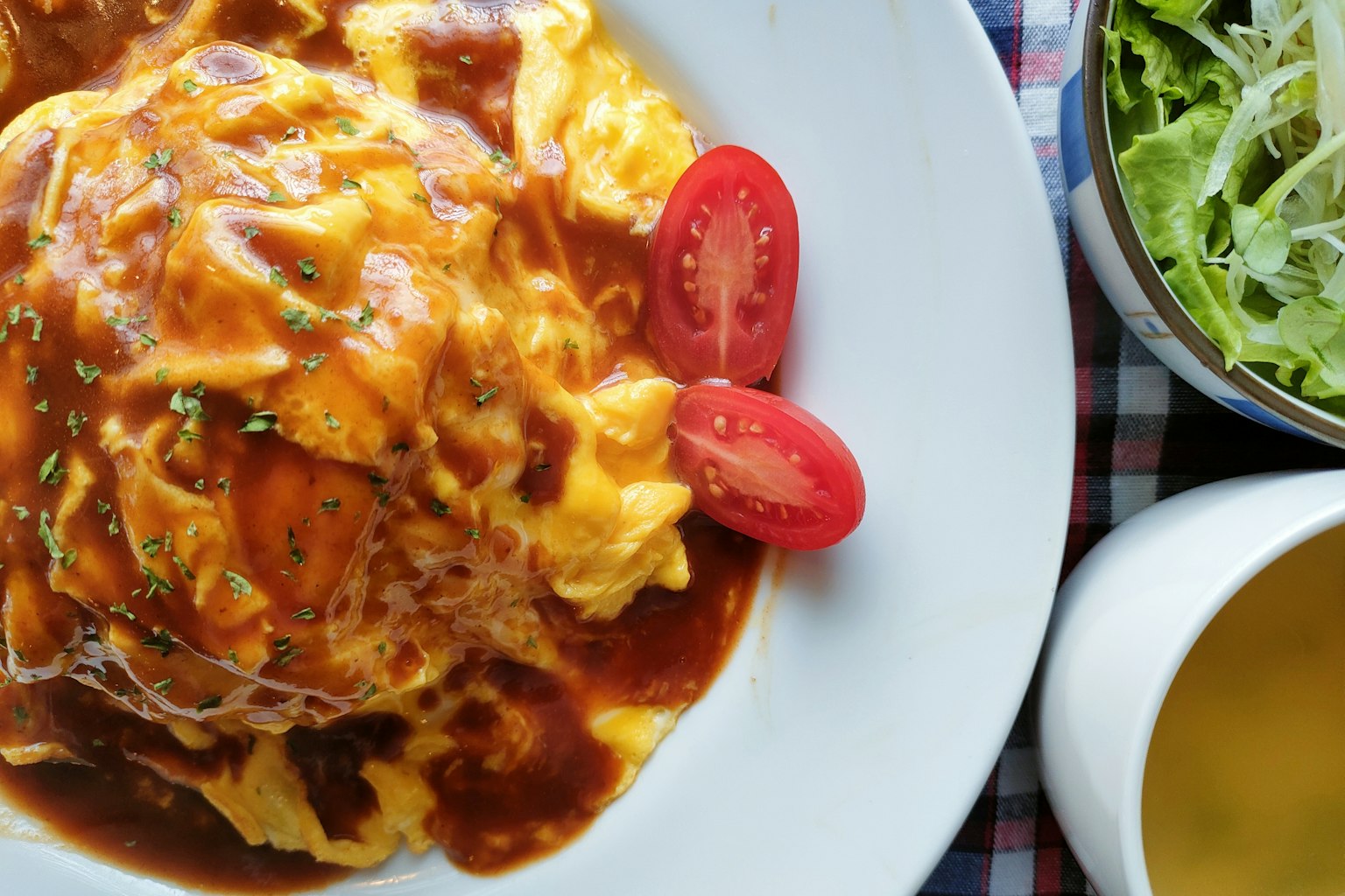 Ein Teller Omelett-Reis mit Tomaten und Salat serviert