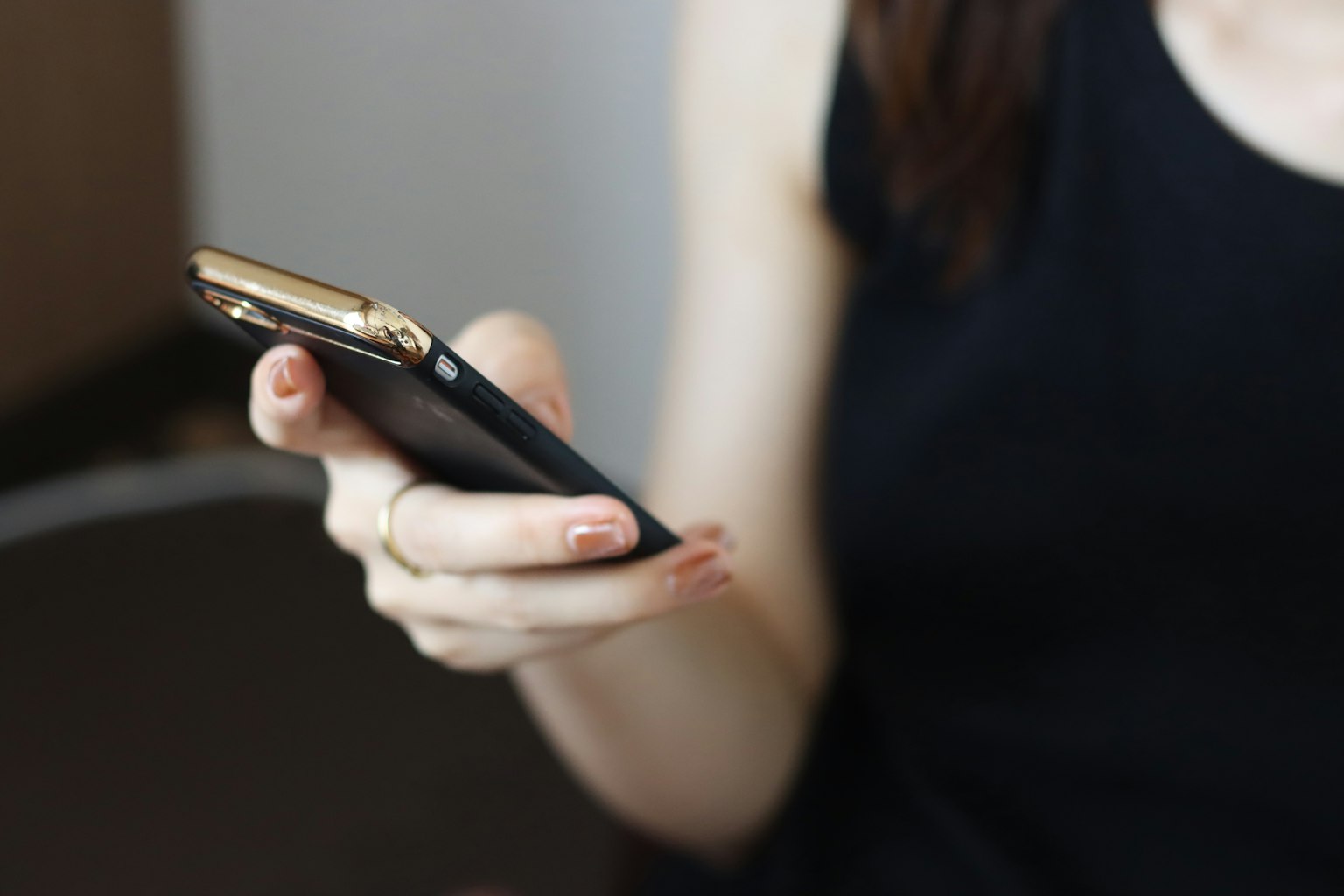 Una mujer sosteniendo un smartphone con un atuendo negro