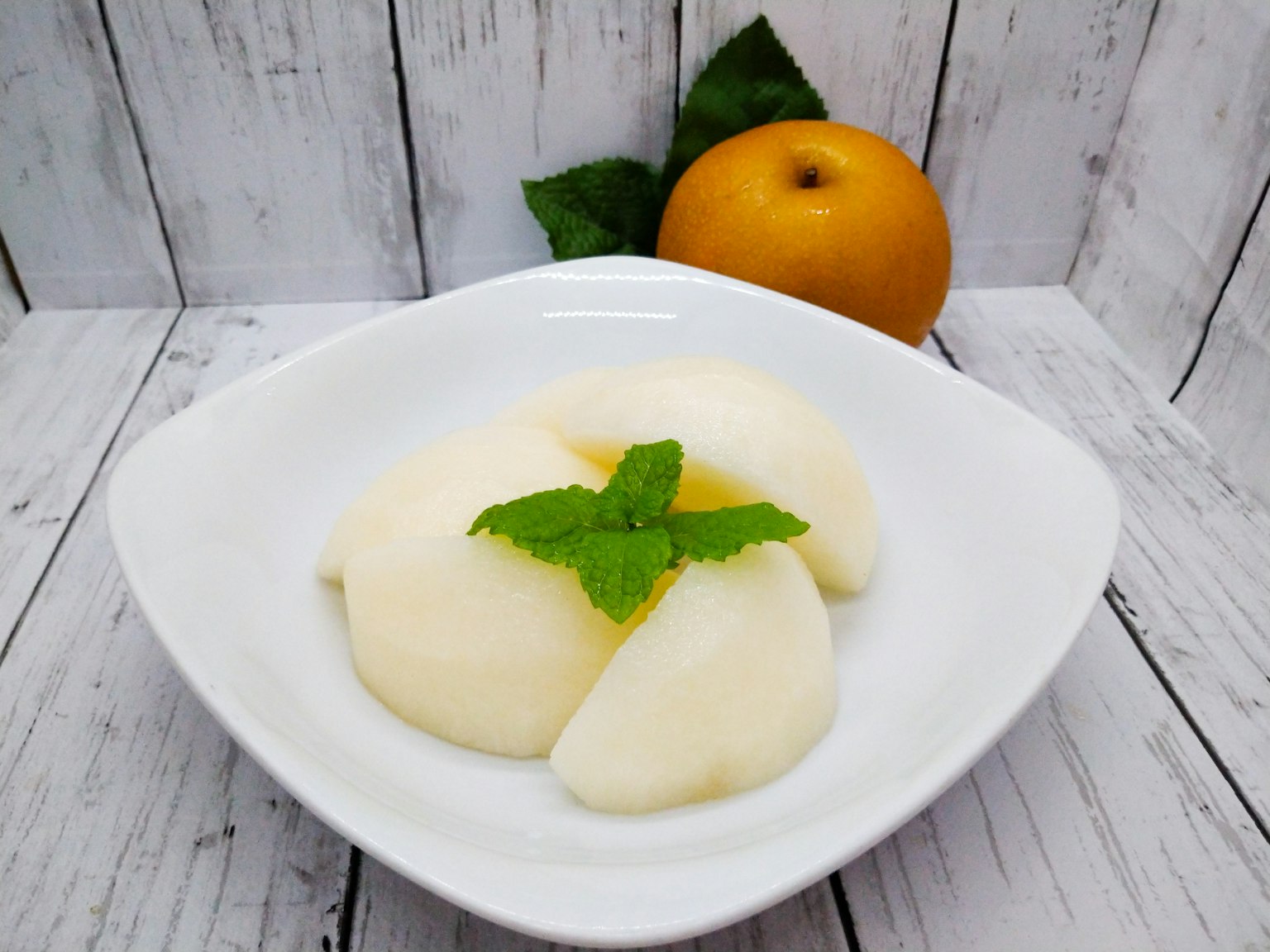 Dessert cremoso servito in una ciotola bianca guarnito con una foglia di menta