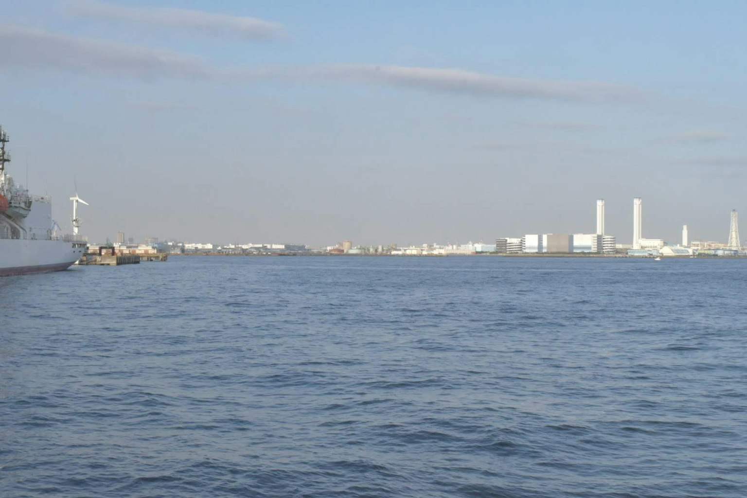 View of the sea with industrial area featuring a ship and smokestacks