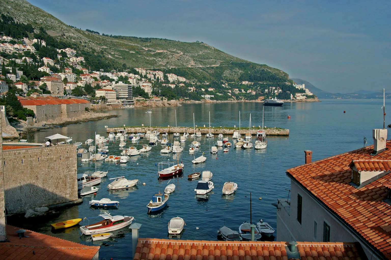 Vista panoramica del porto con barche su acque calme colline verdi sullo sfondo