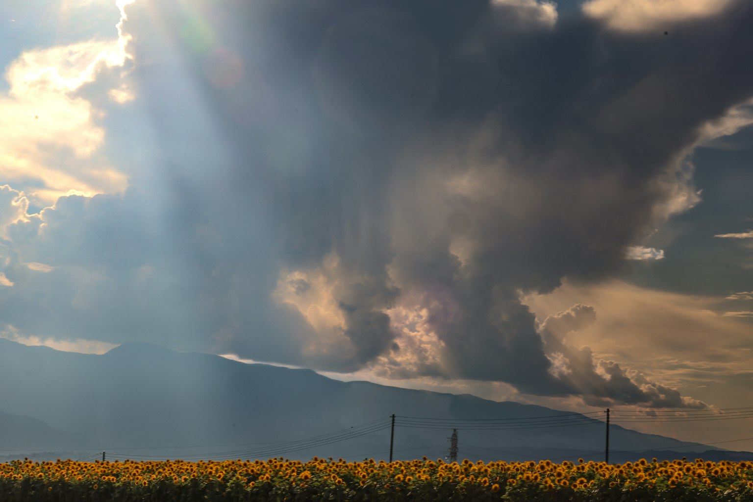 Paesaggio con nuvole drammatiche e raggi di sole dietro le montagne