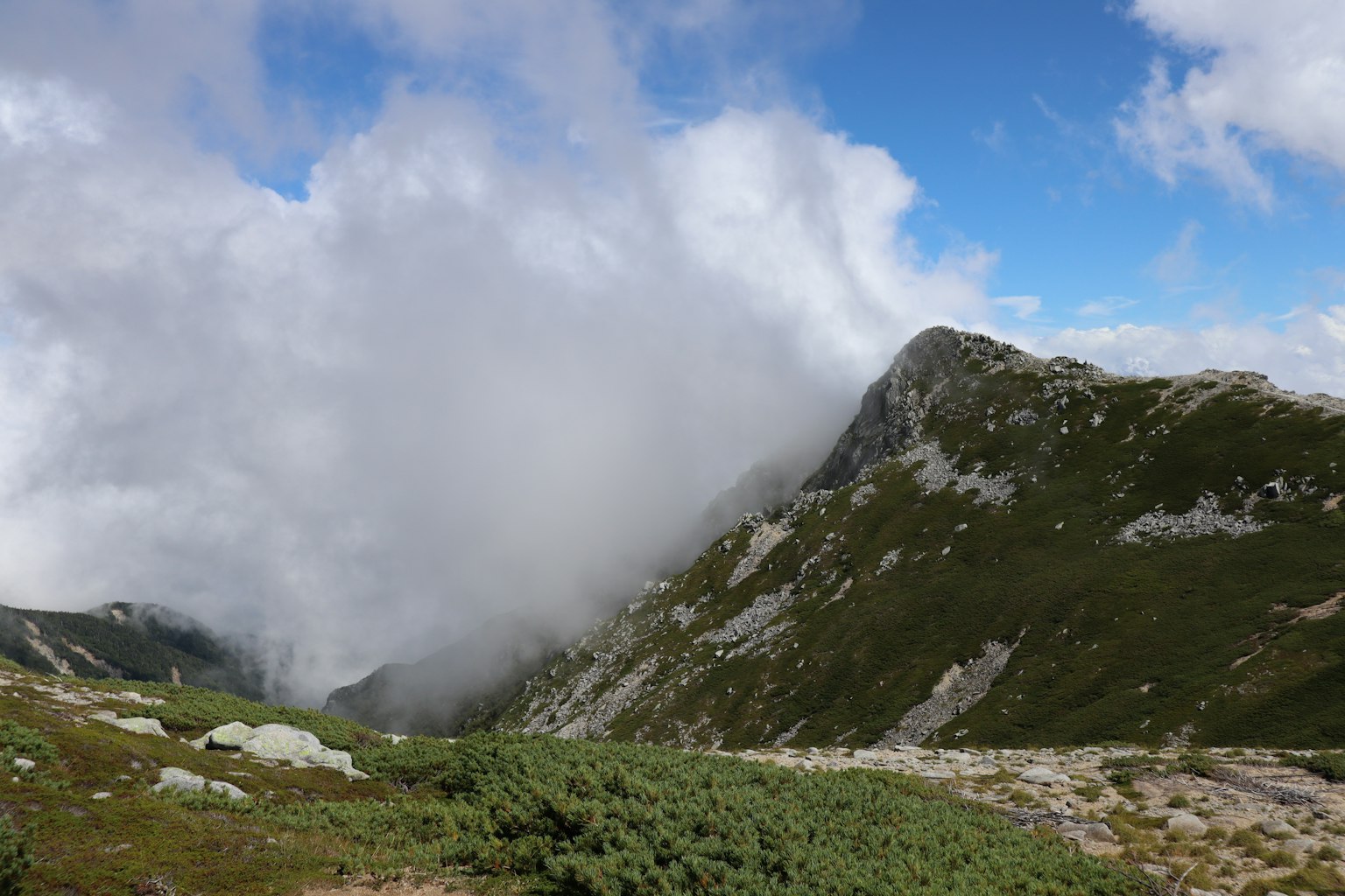 Paysage montagneux couvert de nuages herbe verte et terrain rocheux