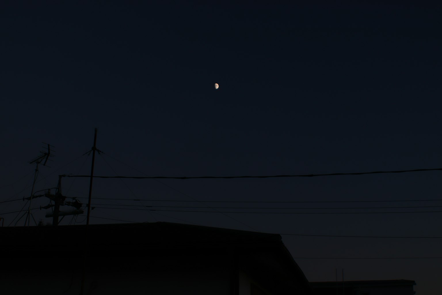 Bulan di langit malam di atas siluet bangunan gelap