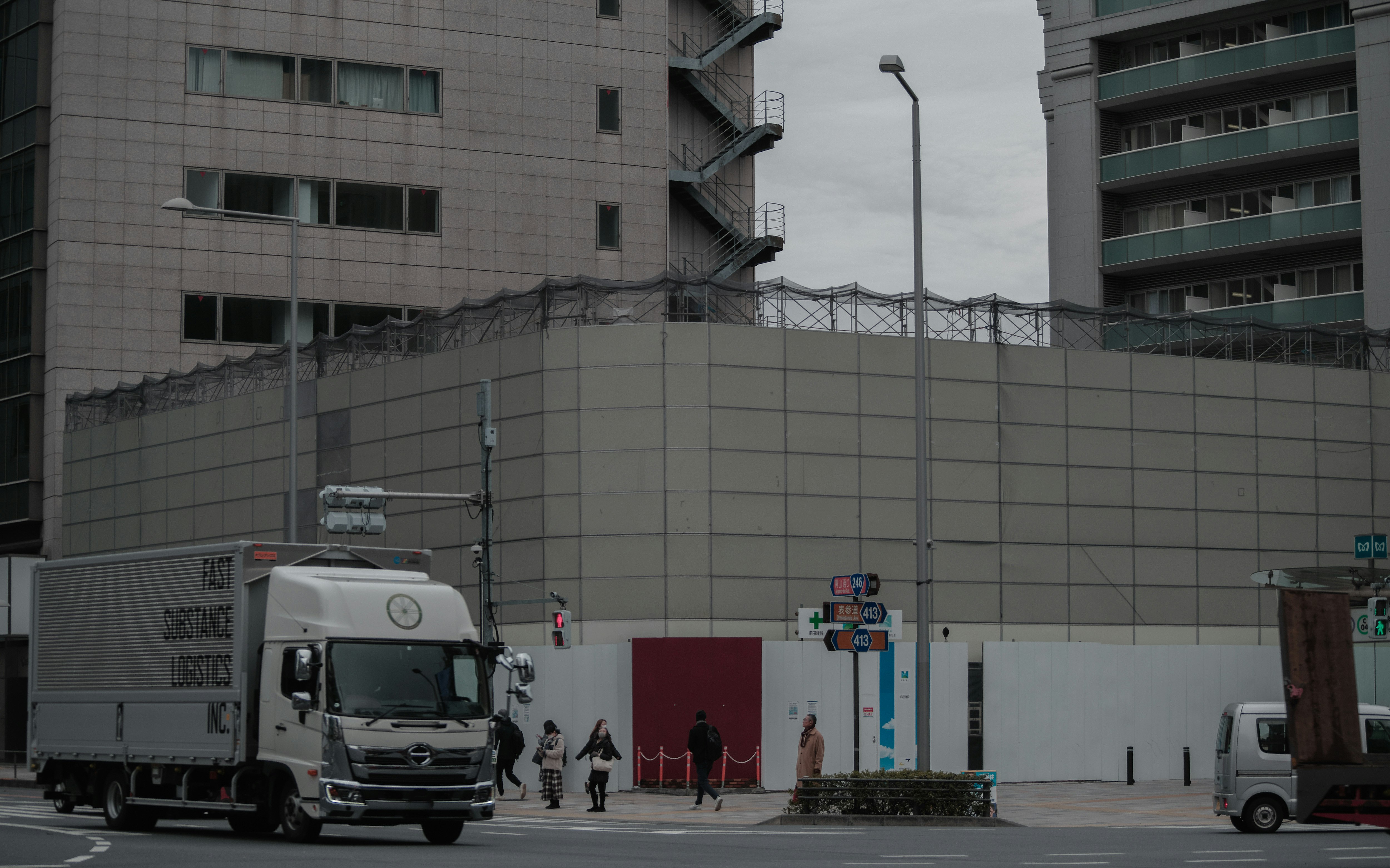ビル街の壁沿いに停車するトラックと小型車