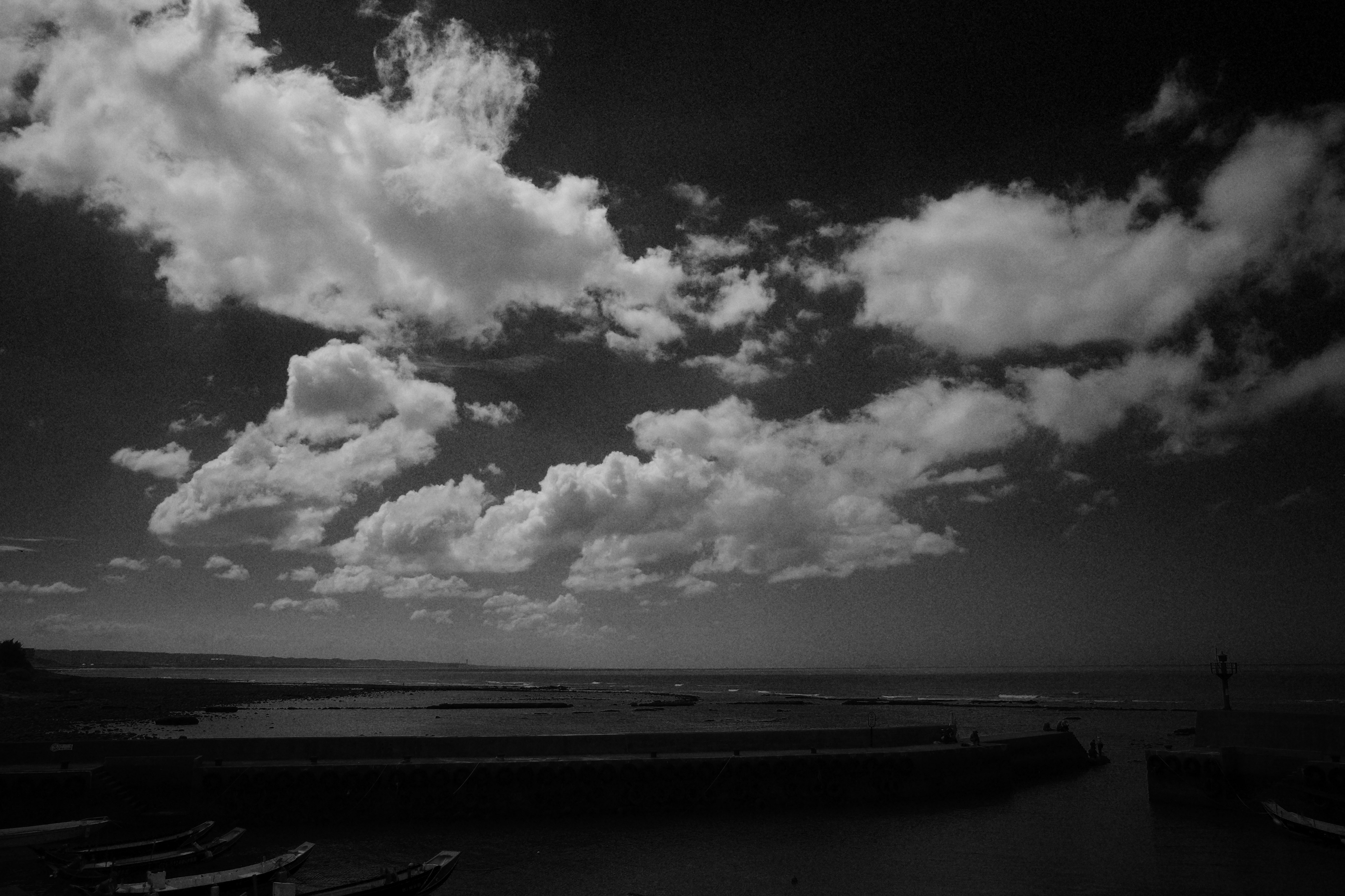 black-and-white seascape with a wide horizon under dramatic clouds