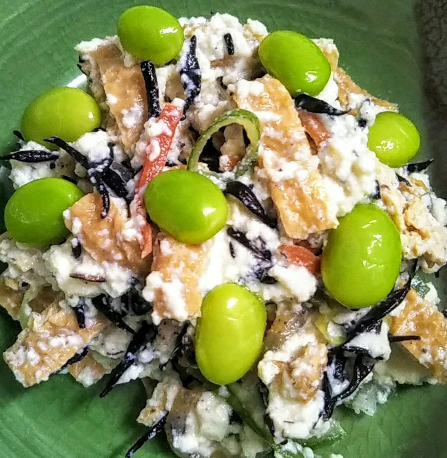 Salad hijiki và đậu phụ được phục vụ trên đĩa xanh với đậu xanh trên cùng