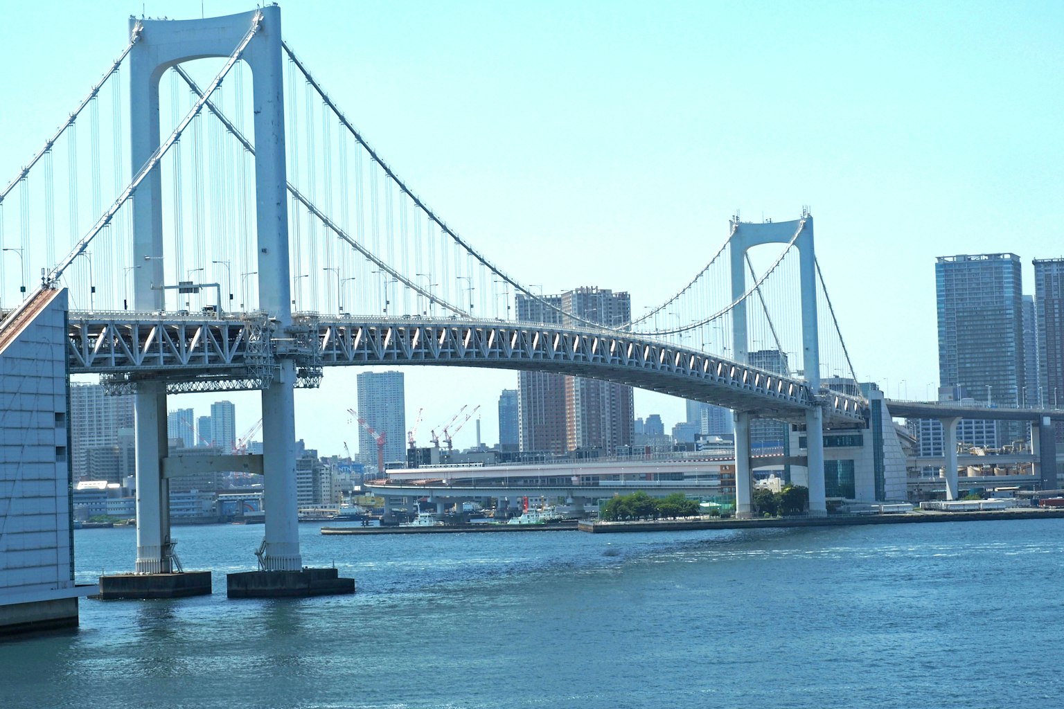 View of Rainbow Bridge with blue sky and city skyline