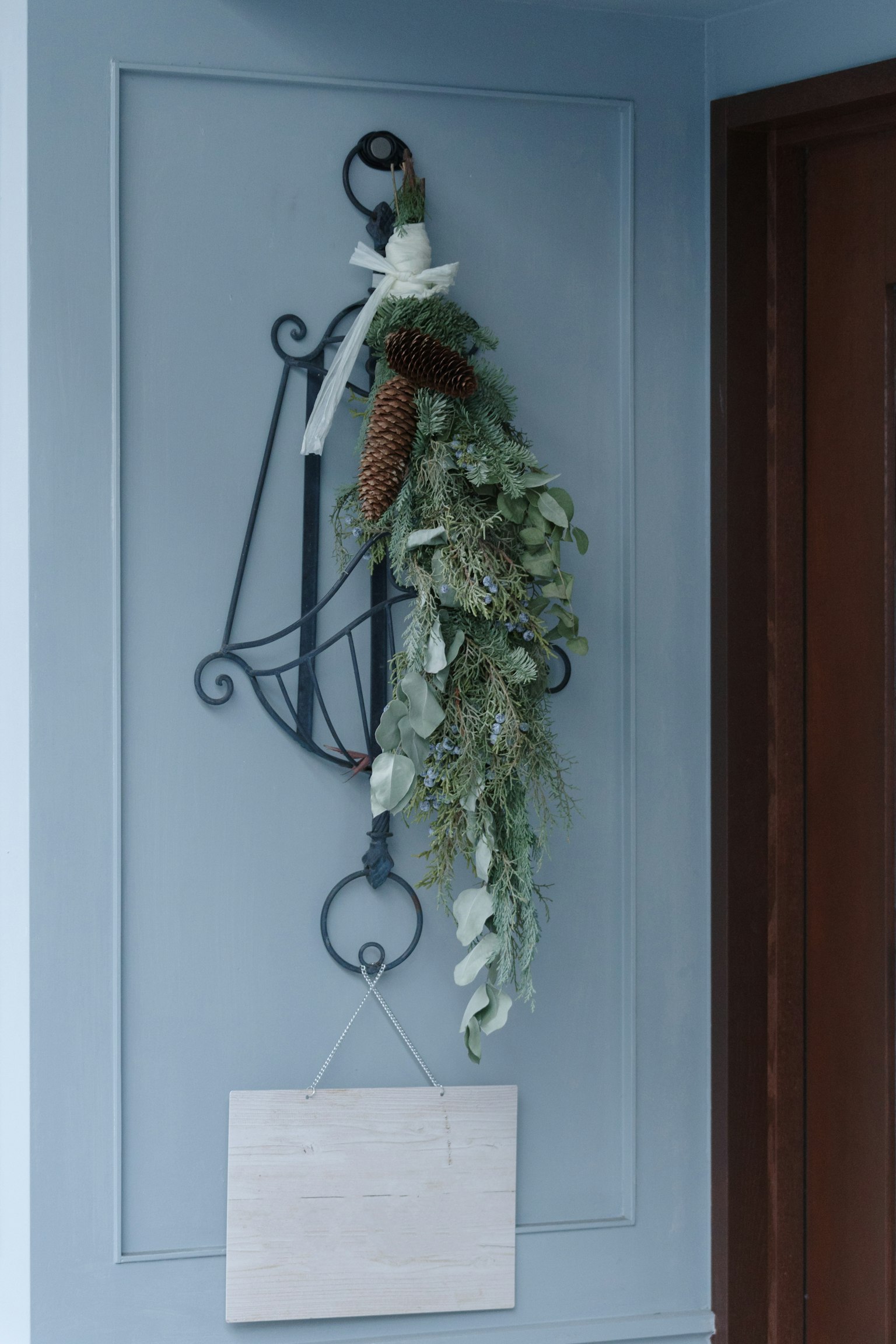 Getrockneter Blumenkranz, der an einer blauen Wand mit einem Metallhaken hängt