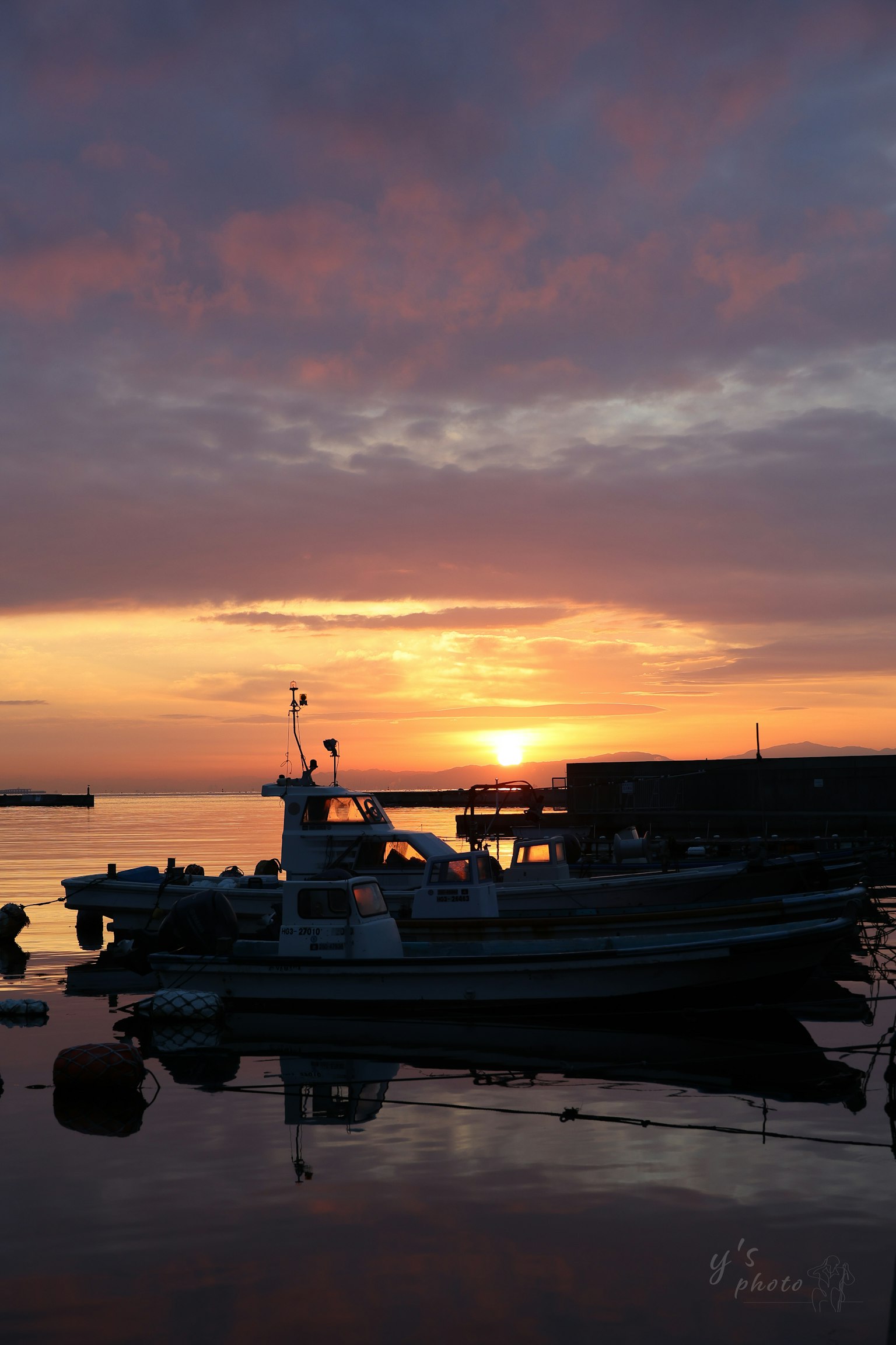 夕焼けの中に浮かぶ漁船と静かな水面
