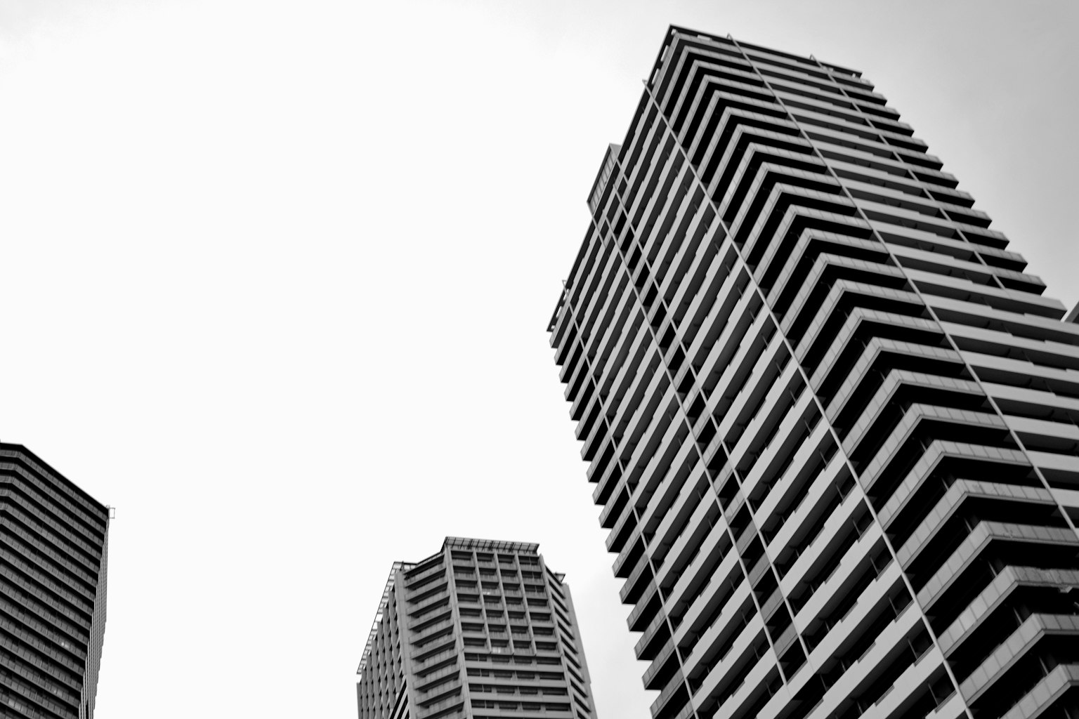Foto en blanco y negro de rascacielos tomada desde un ángulo bajo destacando los balcones escalonados