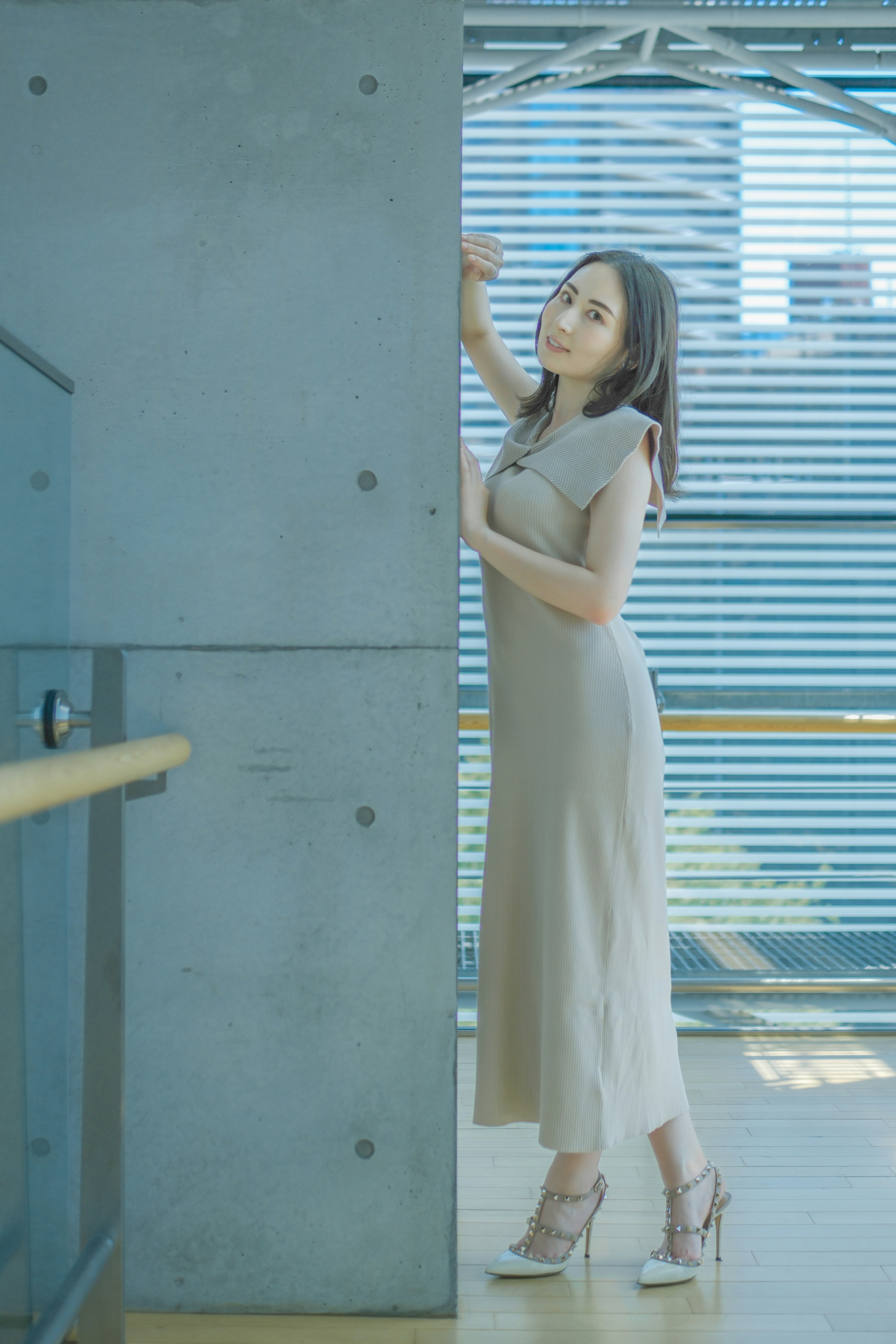 コンクリートの柱のそばに立つ白いワンピースの女性