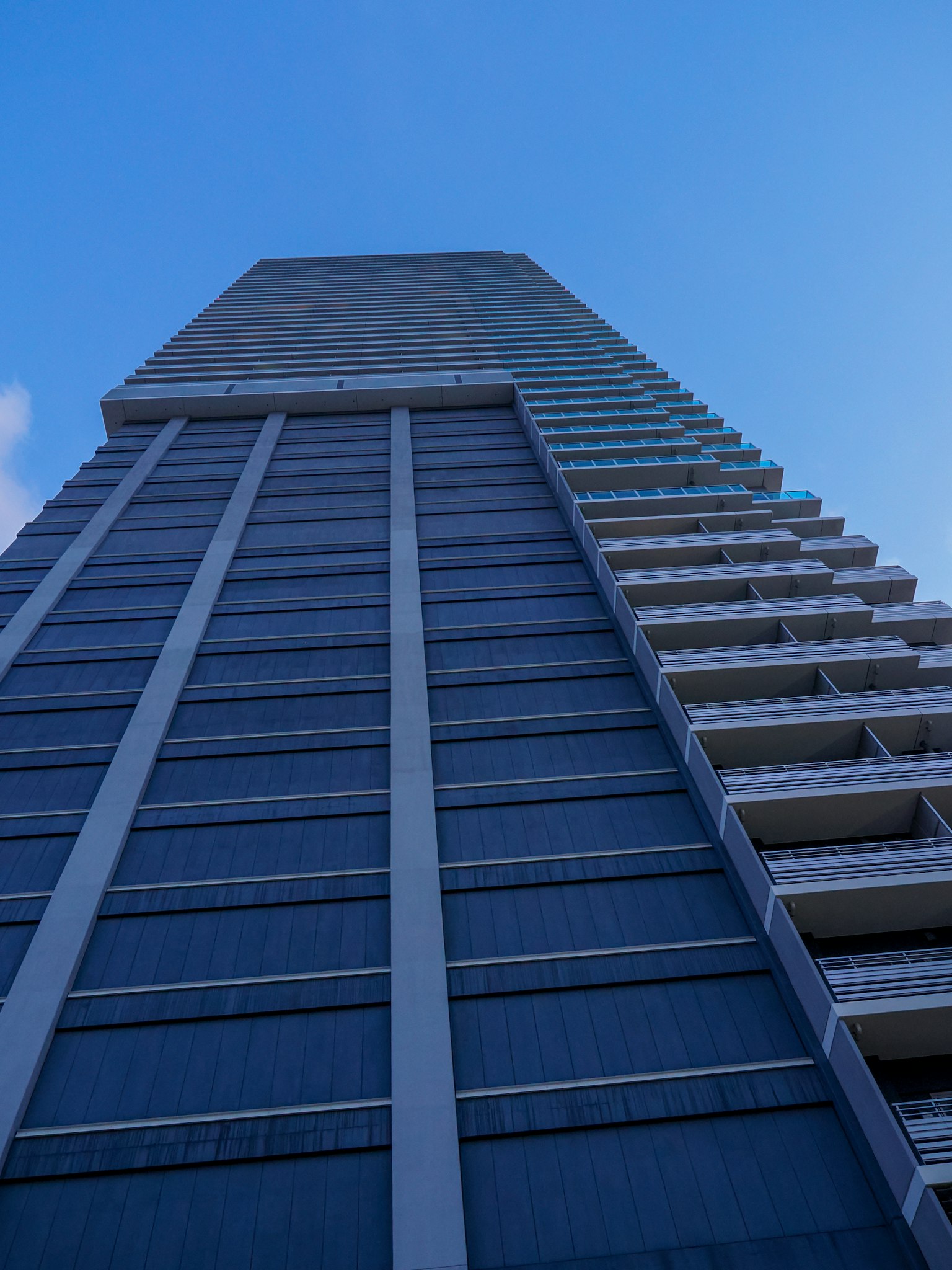 Une photo d'un grand bâtiment vu d'en bas sous un ciel bleu avec une façade bleue