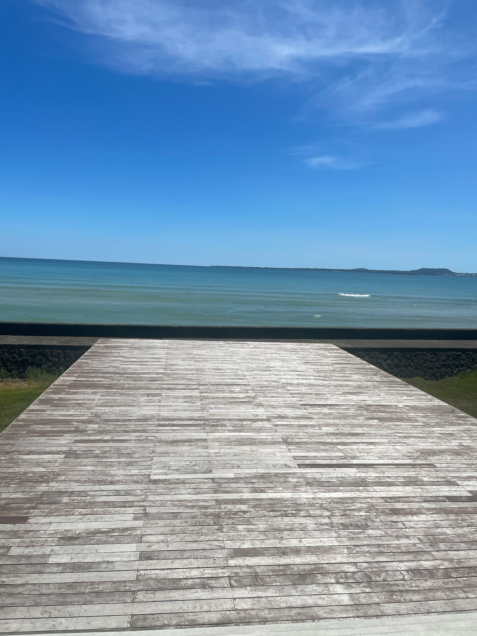 Terrazza in legno che si affaccia su un mare calmo e un cielo blu