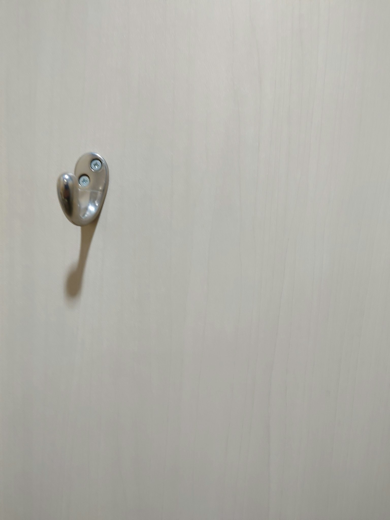 Metal hook attached to a white wall with a simple design