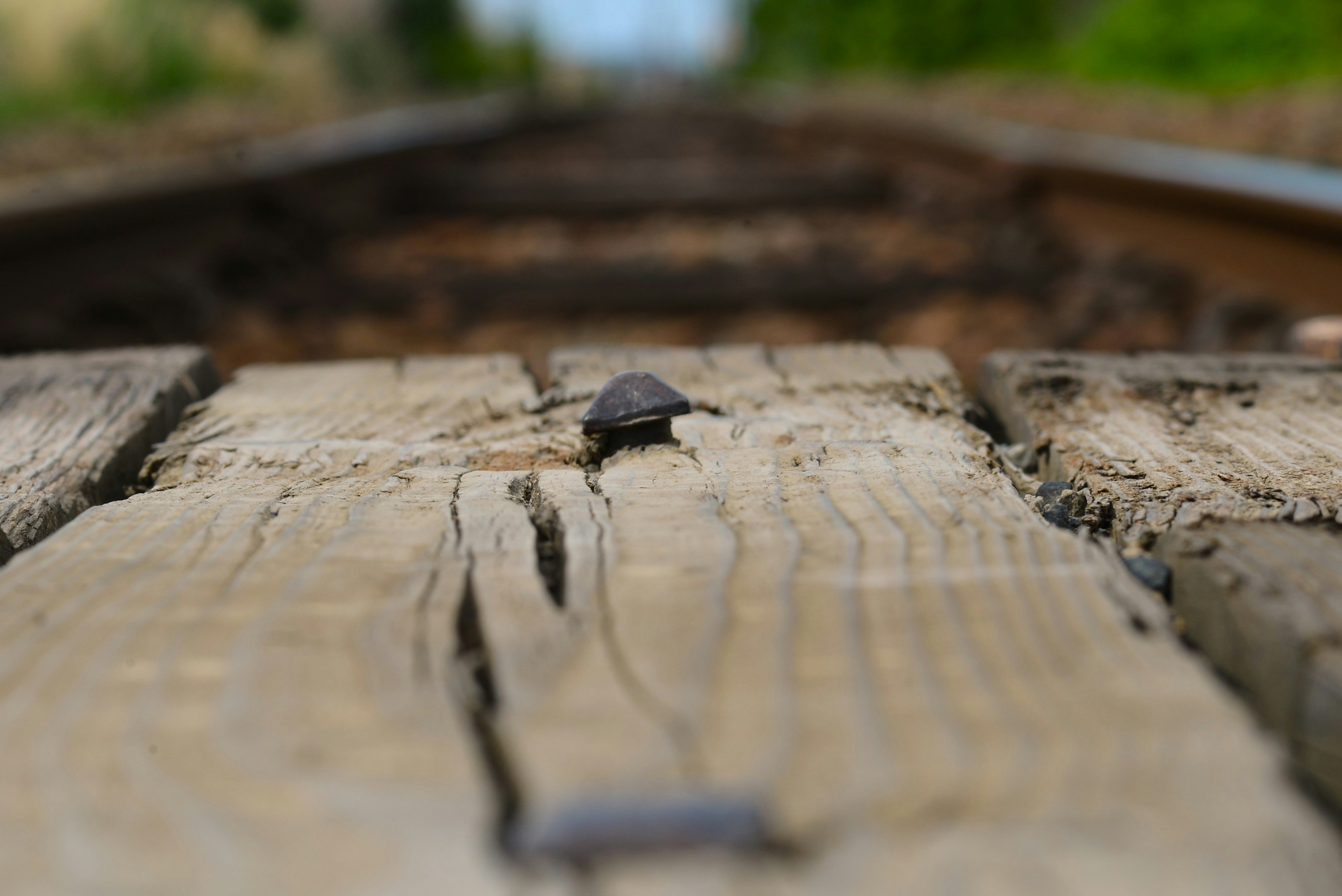 close-up rel kereta api lokal yang memanjang ke depan