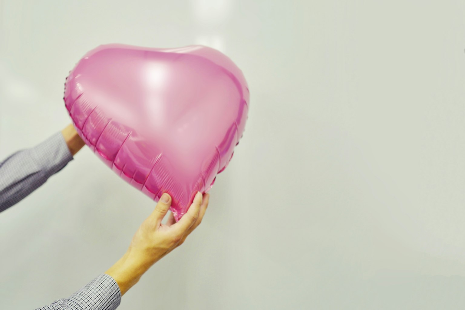 Hände halten einen rosa Herzballon