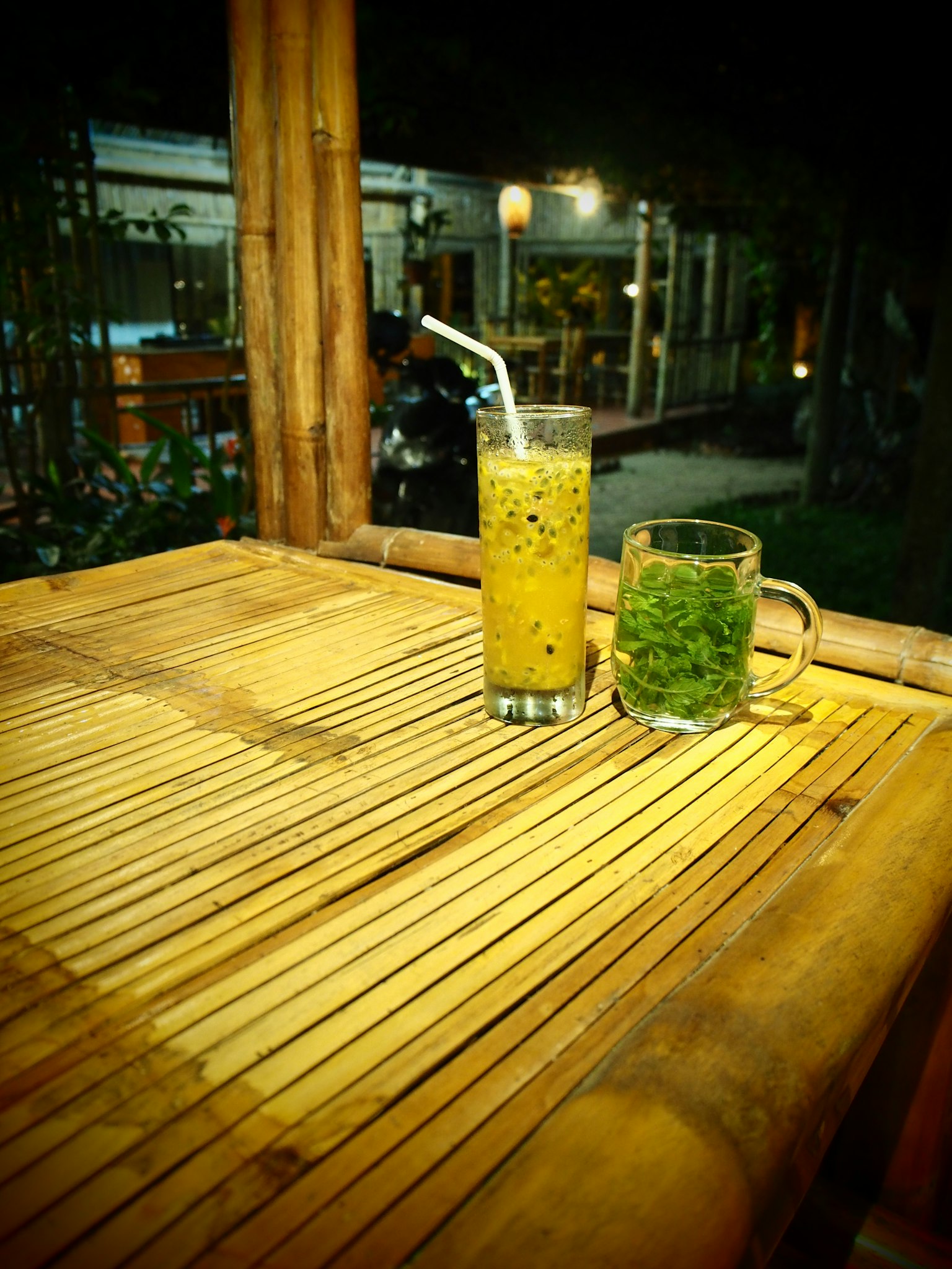 夜晚竹桌上的飲料和一杯草藥