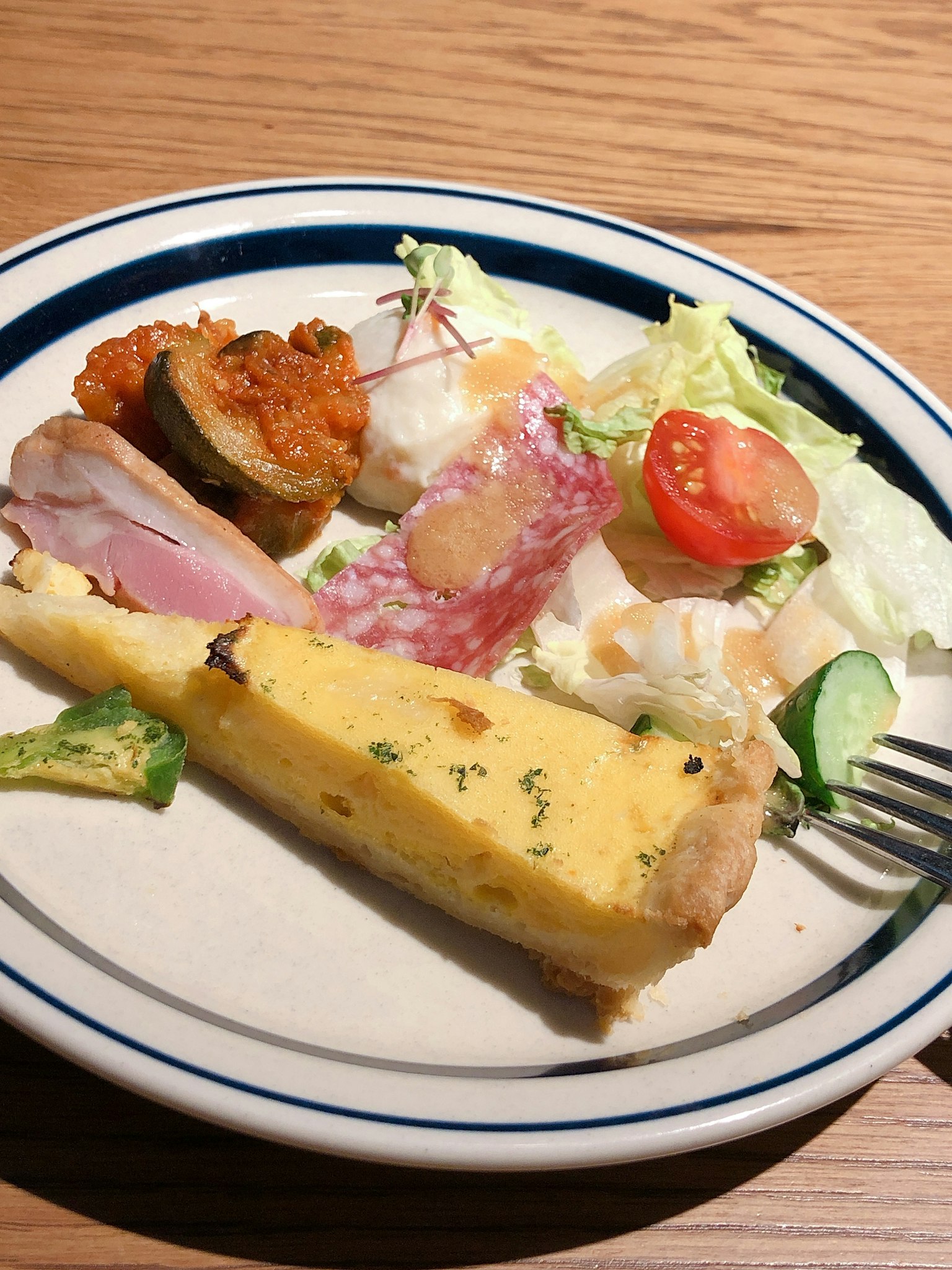 Ein Teller mit Salat, Schinken, Tomaten und einem Stück Eiergericht