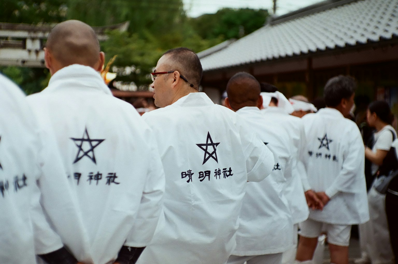 穿著白色衣服的男性排成一行 背上有星形符號和文字