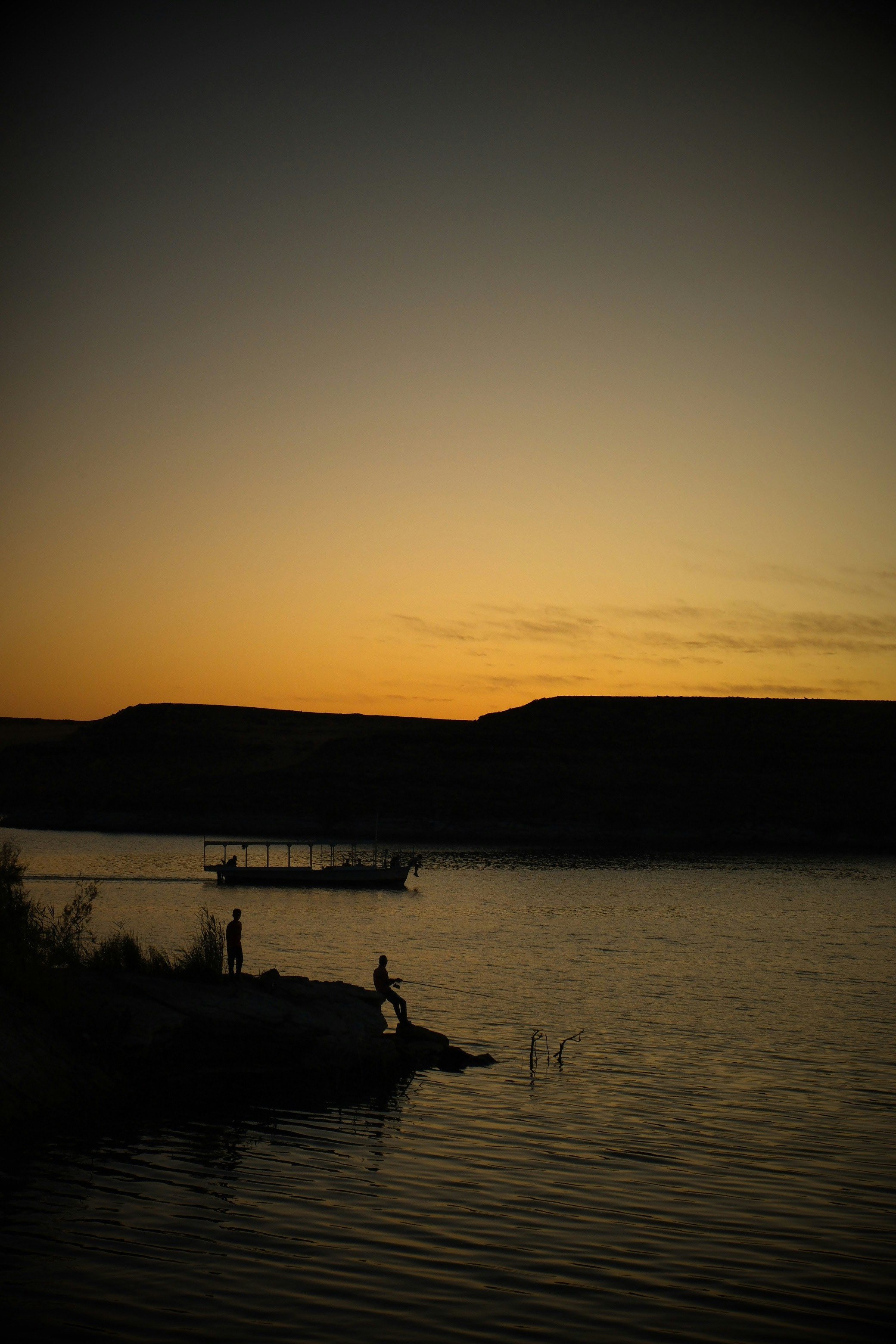 夕暮れの湖畔で人が歩く風景