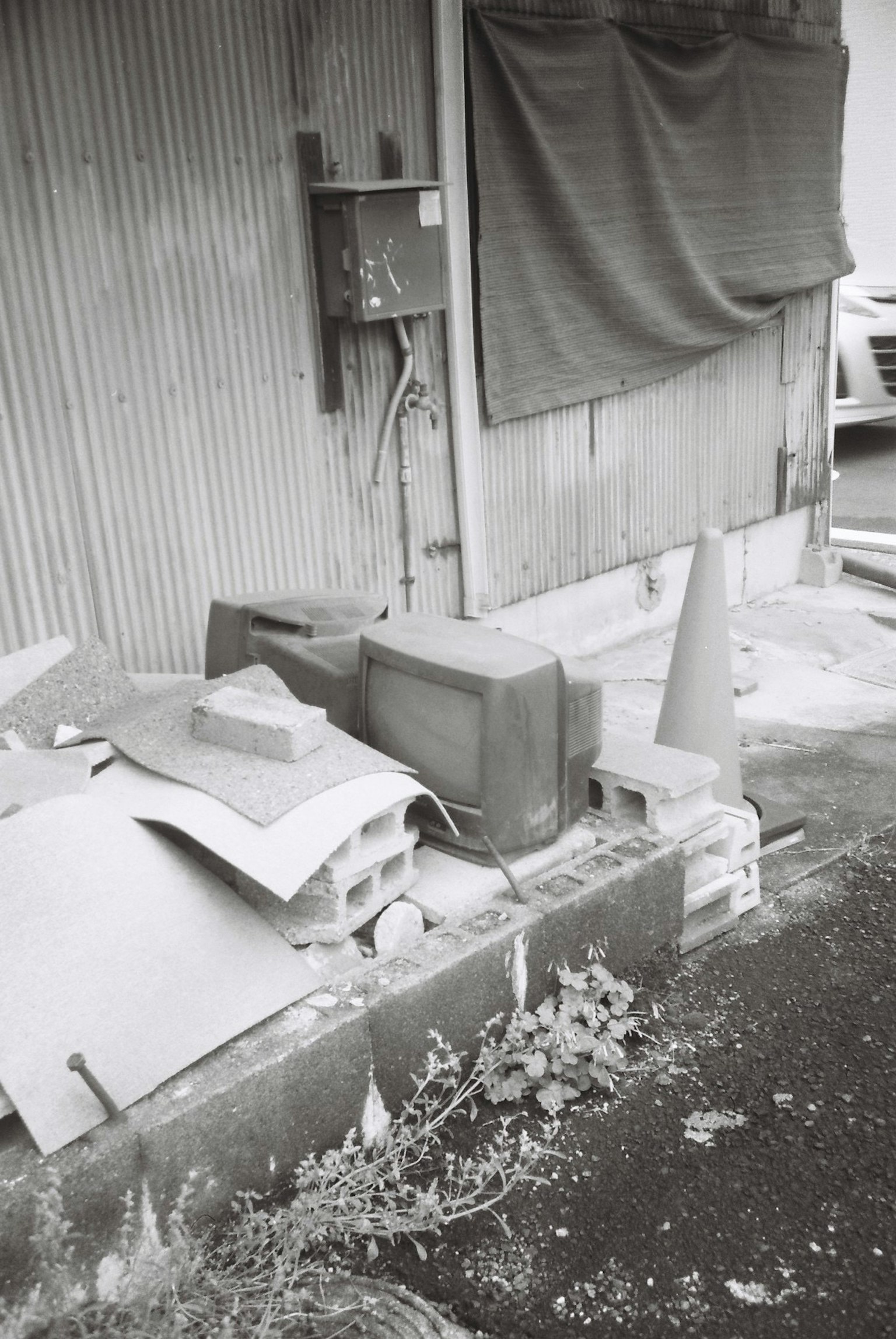 廃棄物が散乱した場所に置かれた古いテレビとコーンが写っている