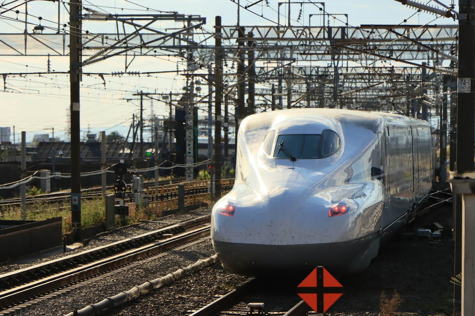 รถไฟชินคันเซ็นจอดอยู่บนรางพร้อมสายไฟเหนือศีรษะ