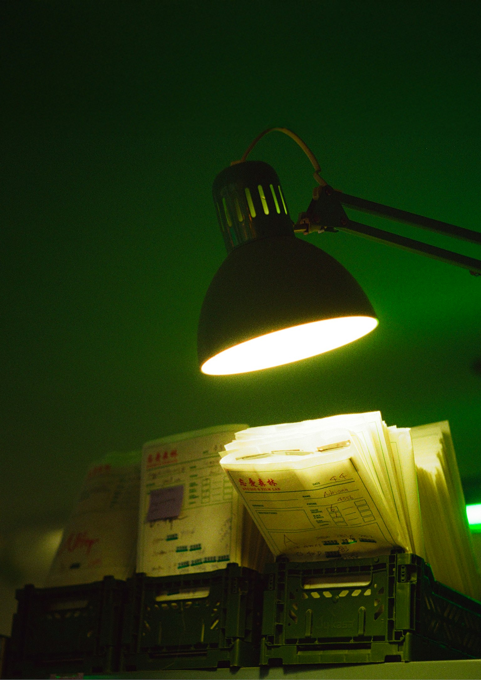 Une pile de documents éclairée par une lampe de bureau sur fond vert